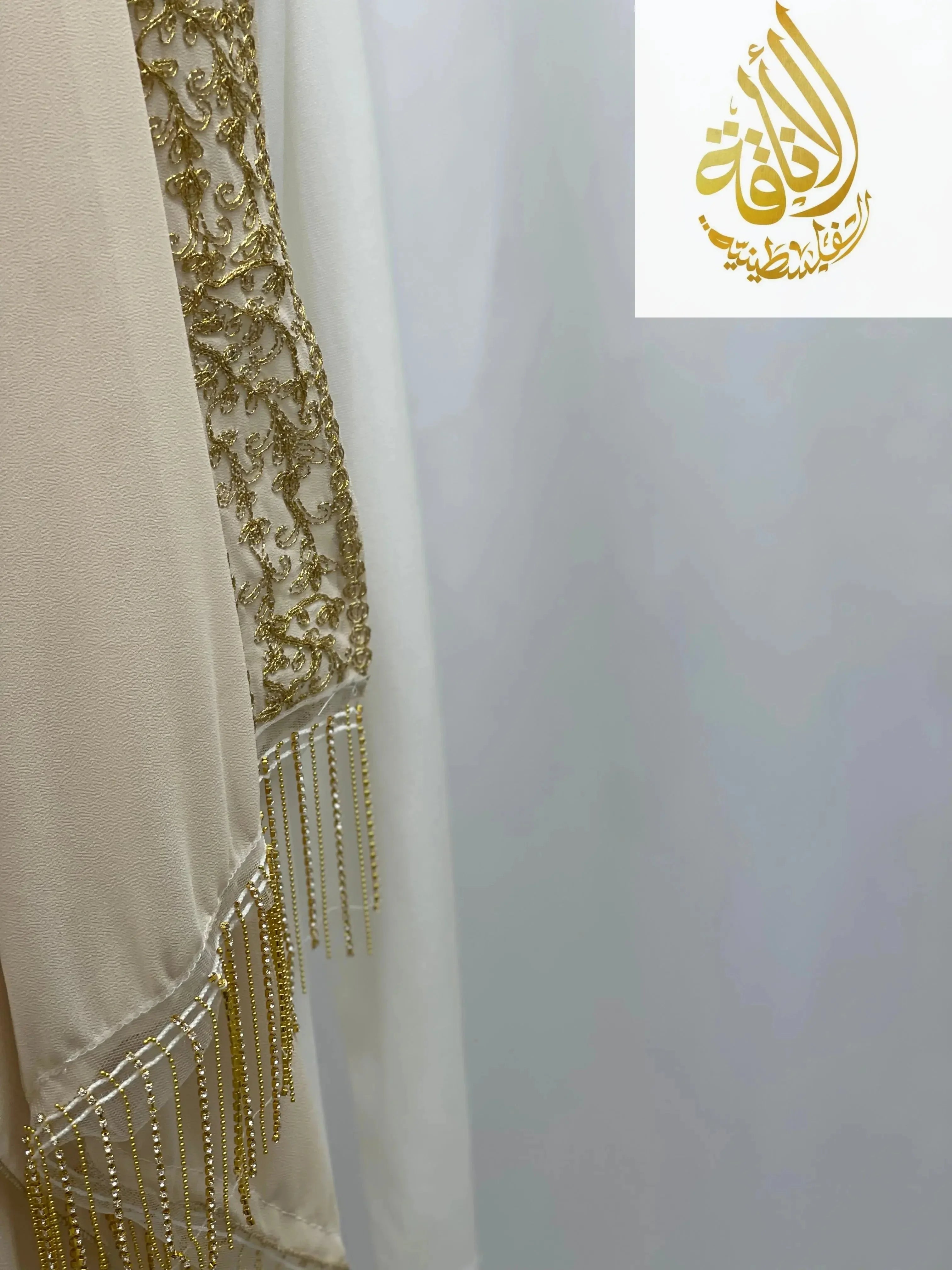 Close-up of Palestinian Traditional Modest Fashion Kasab Khirka embroidery with gold thread and bead fringe detail