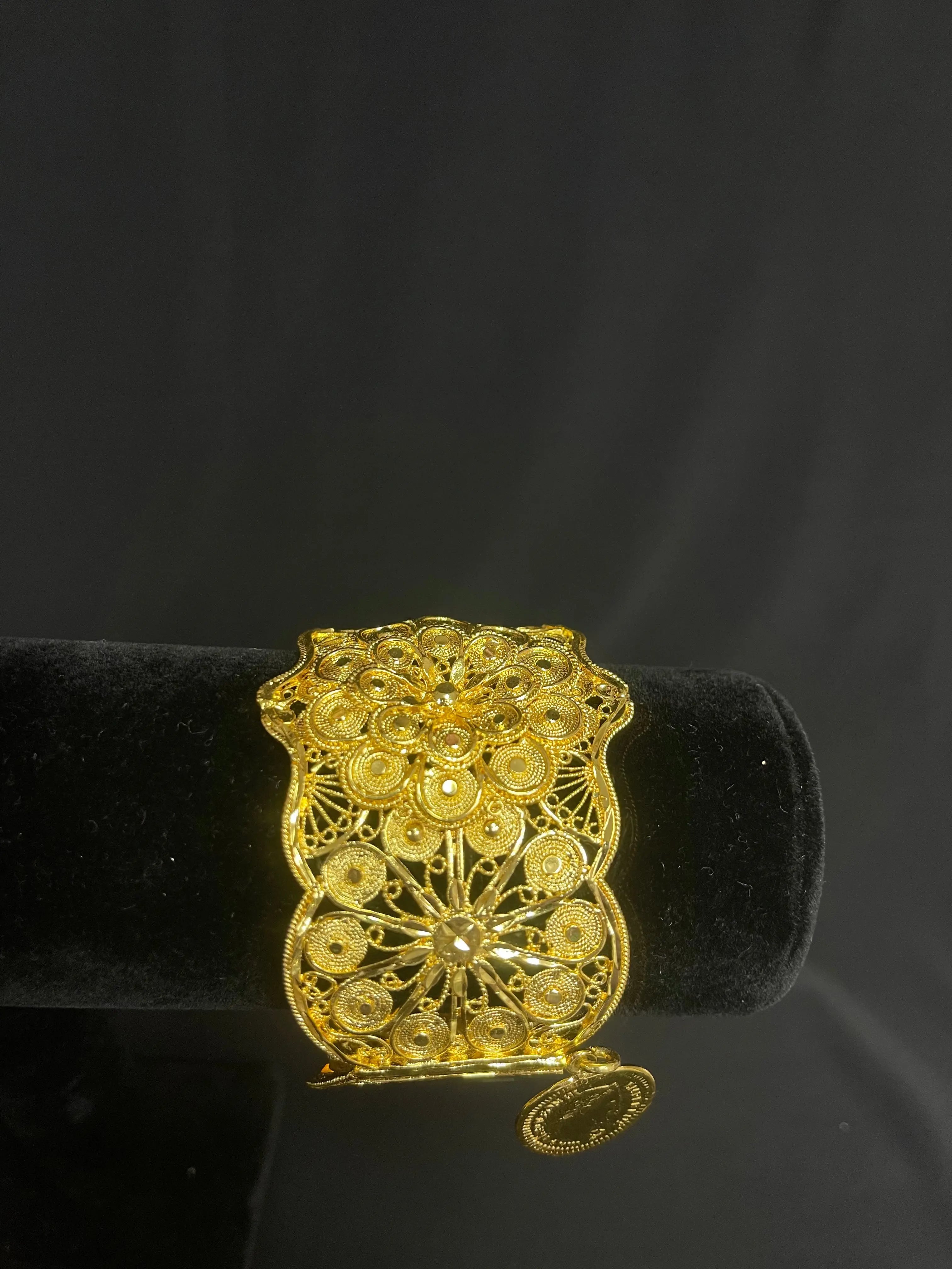 Intricate Palestinian Elegance imitated gold bracelet with floral filigree design on black display