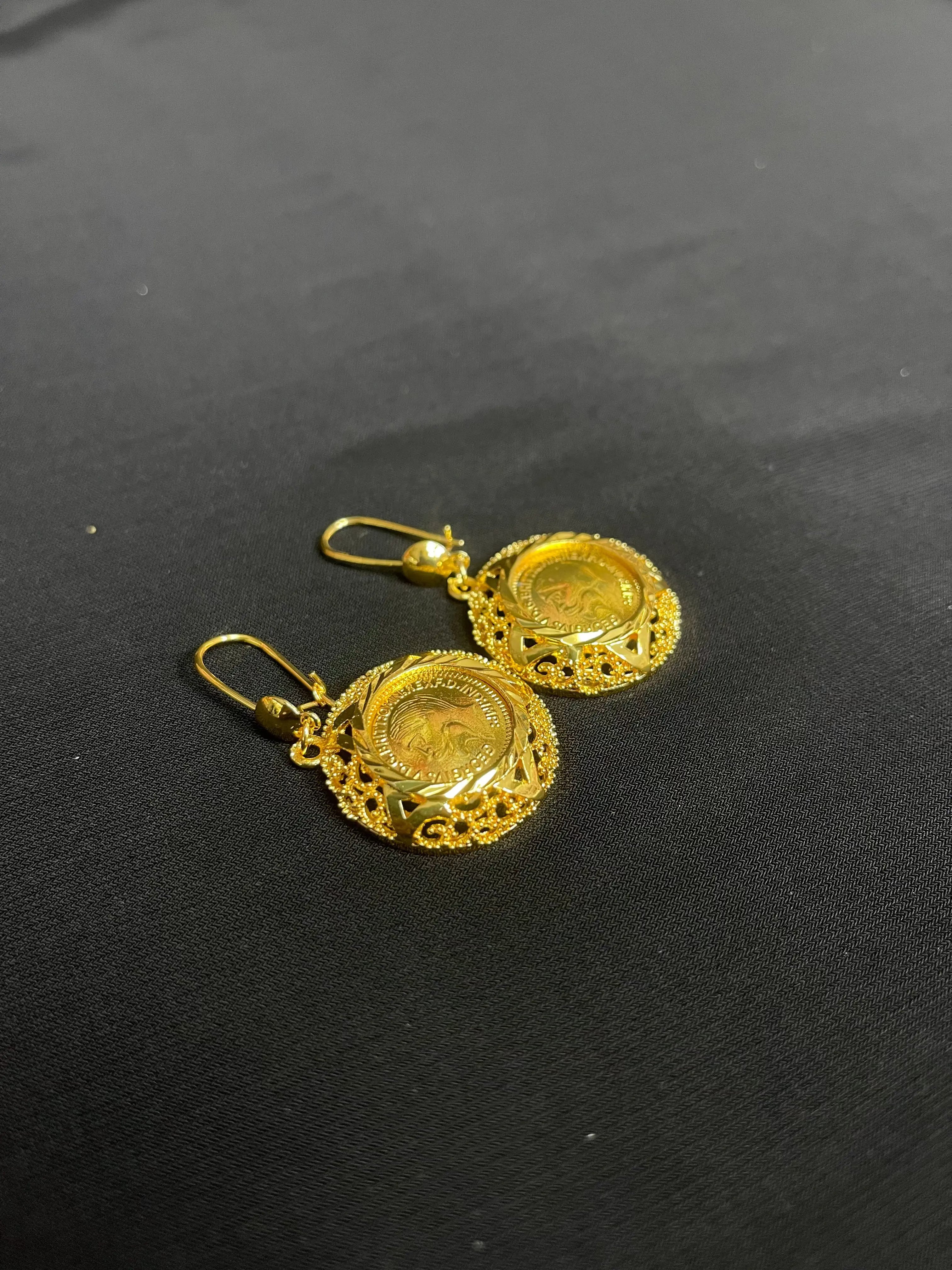 Palestinian Elegance imitation gold circle earrings with intricate filigree design on black background