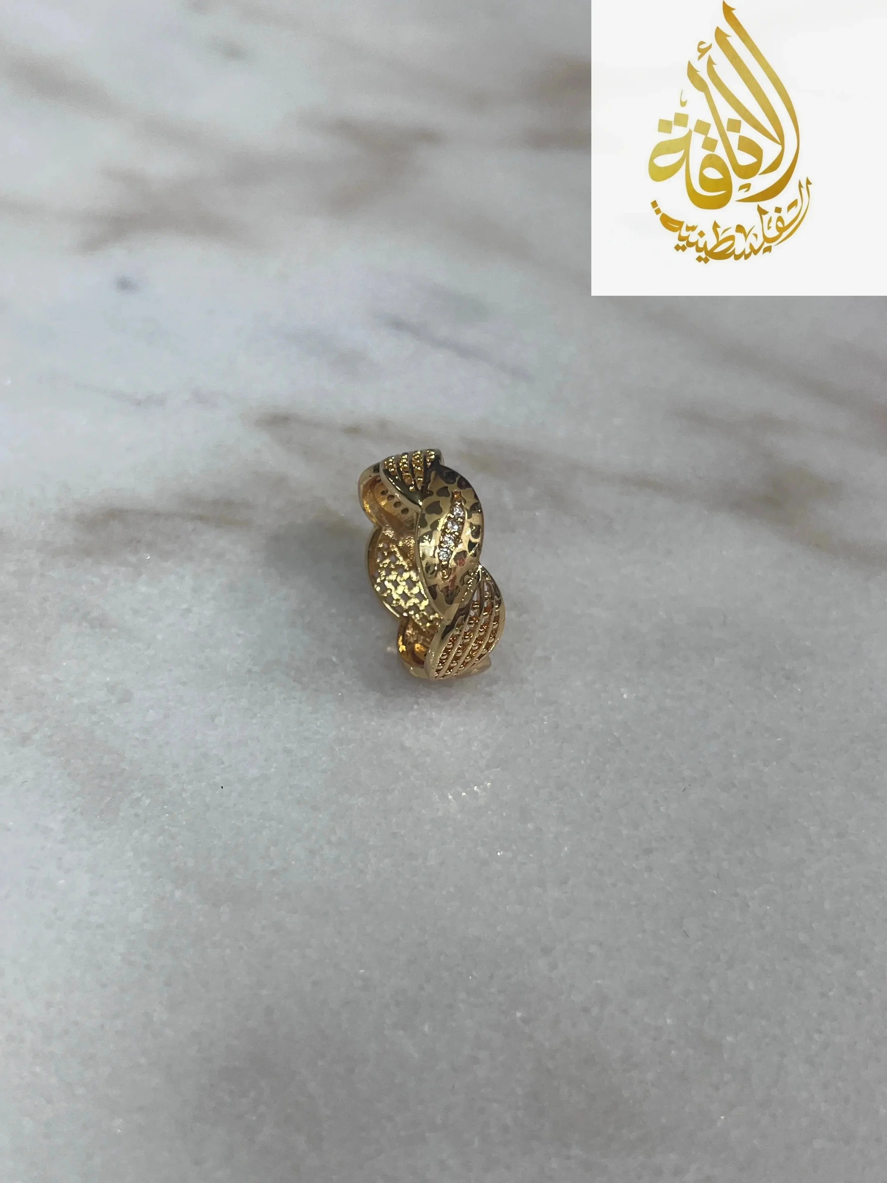Palestinian Elegance imitation gold heart ring with intricate textured design on marble surface