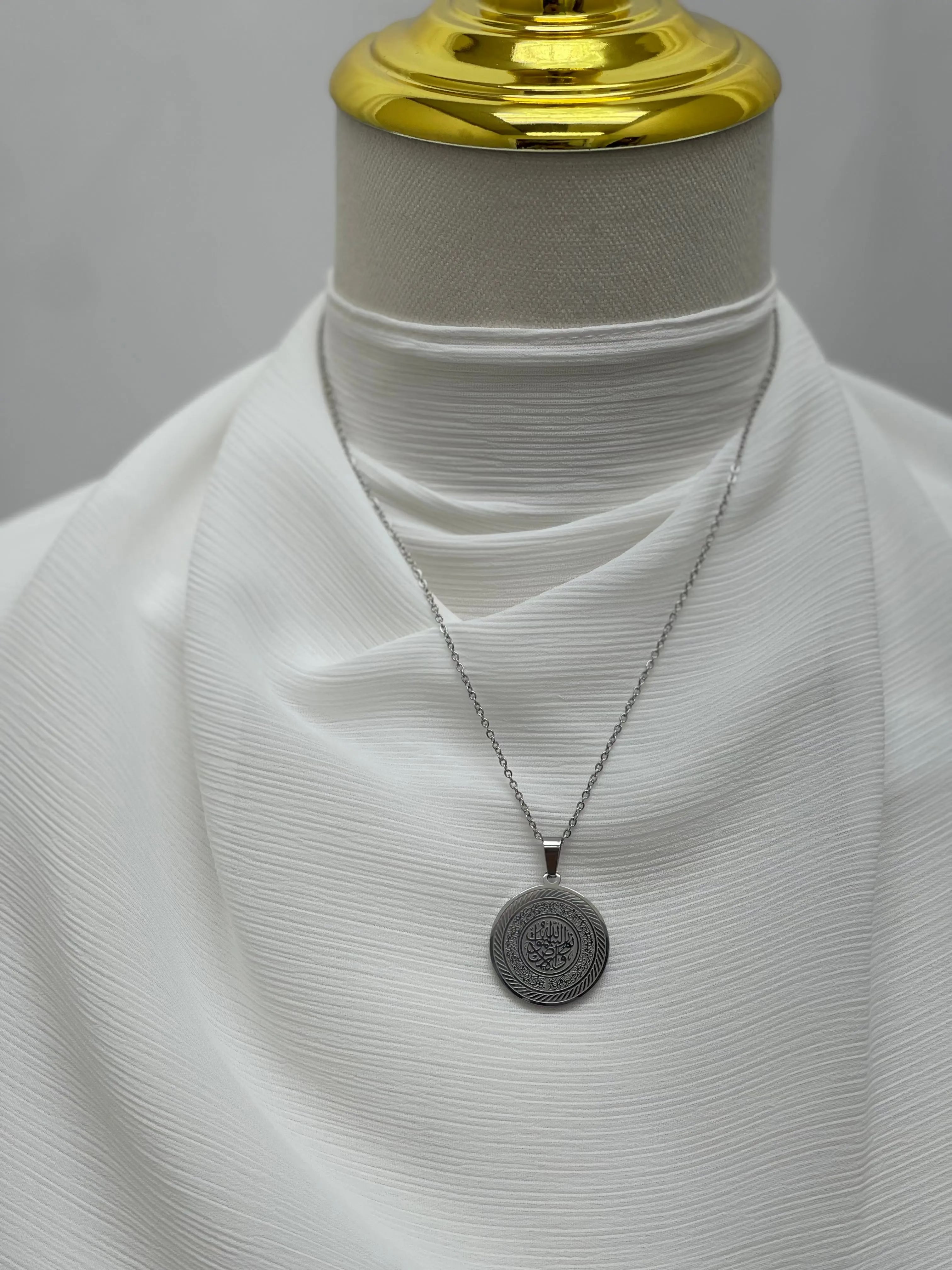 Elegant silver circle necklace with intricate design on a white fabric display by Palestinian Elegance