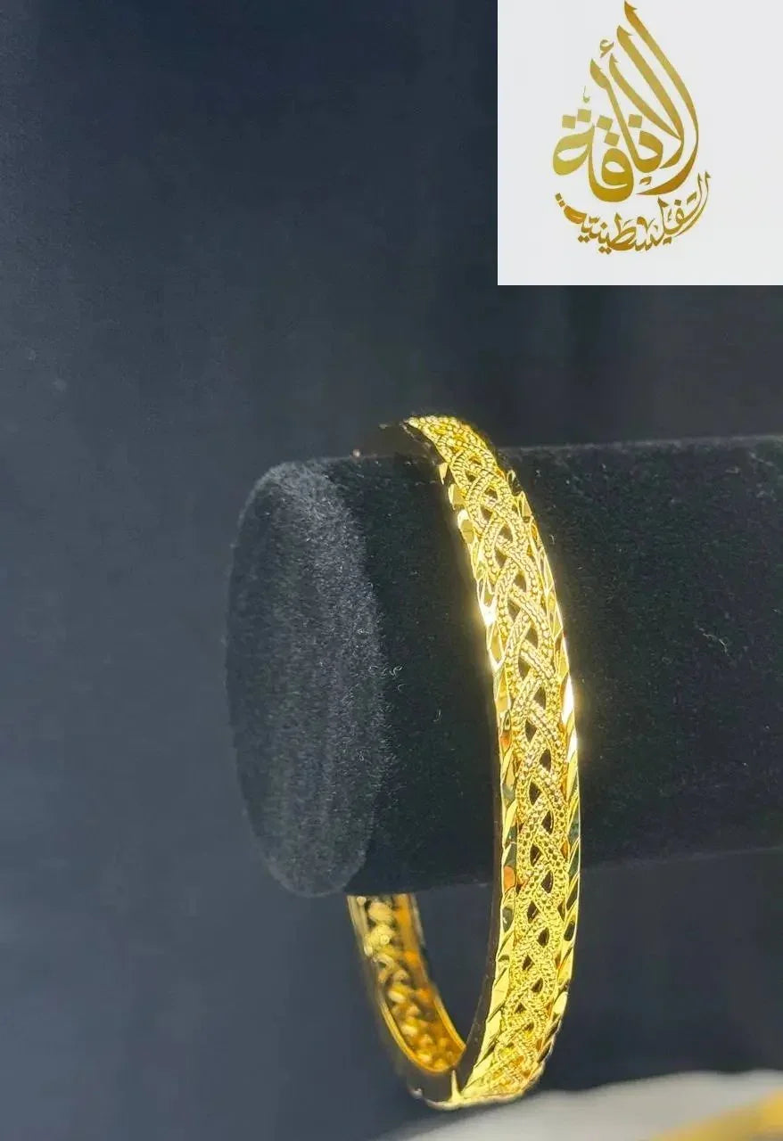 Palestinian Elegance imitation gold bangle bracelet with intricate filigree design on black display