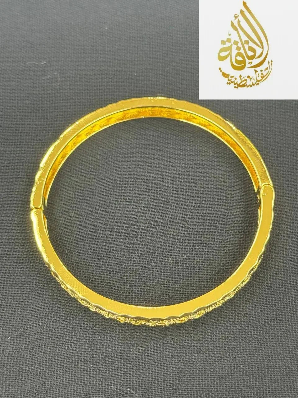 Palestinian Elegance imitation gold bangle bracelet with smooth and textured design on black background