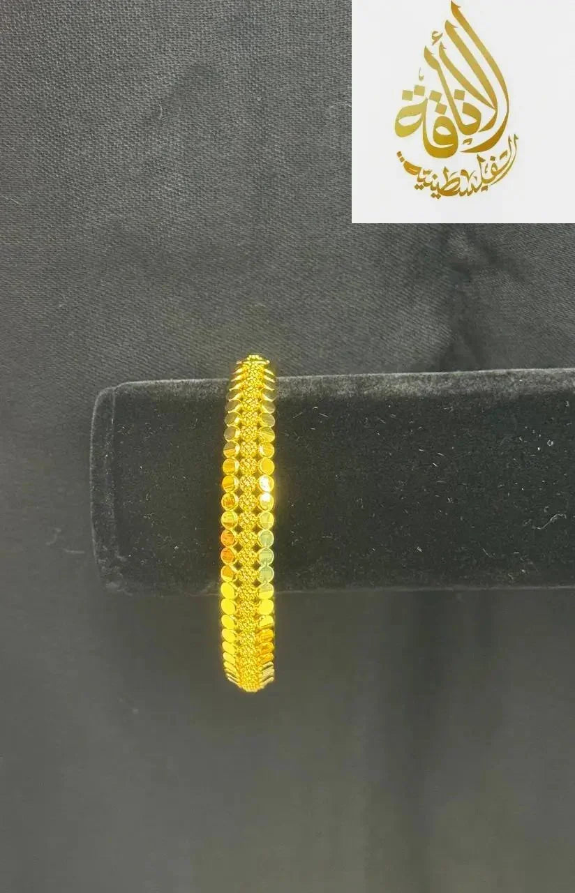 Palestinian Elegance imitation gold bangle bracelet with intricate textured design on black display