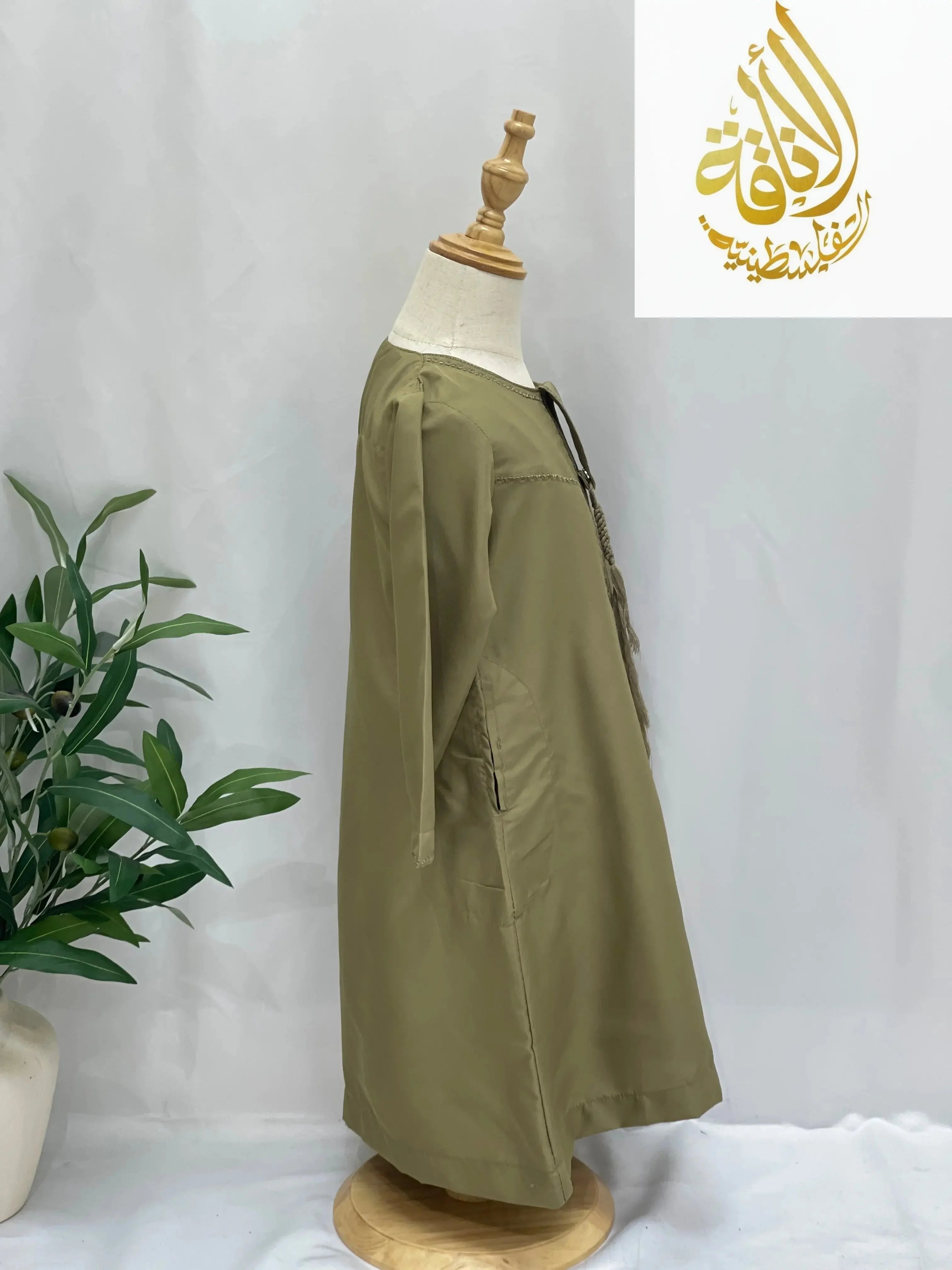 Kids thobe with detachable sharshoba in olive green displayed on mannequin by Palestinian Elegance