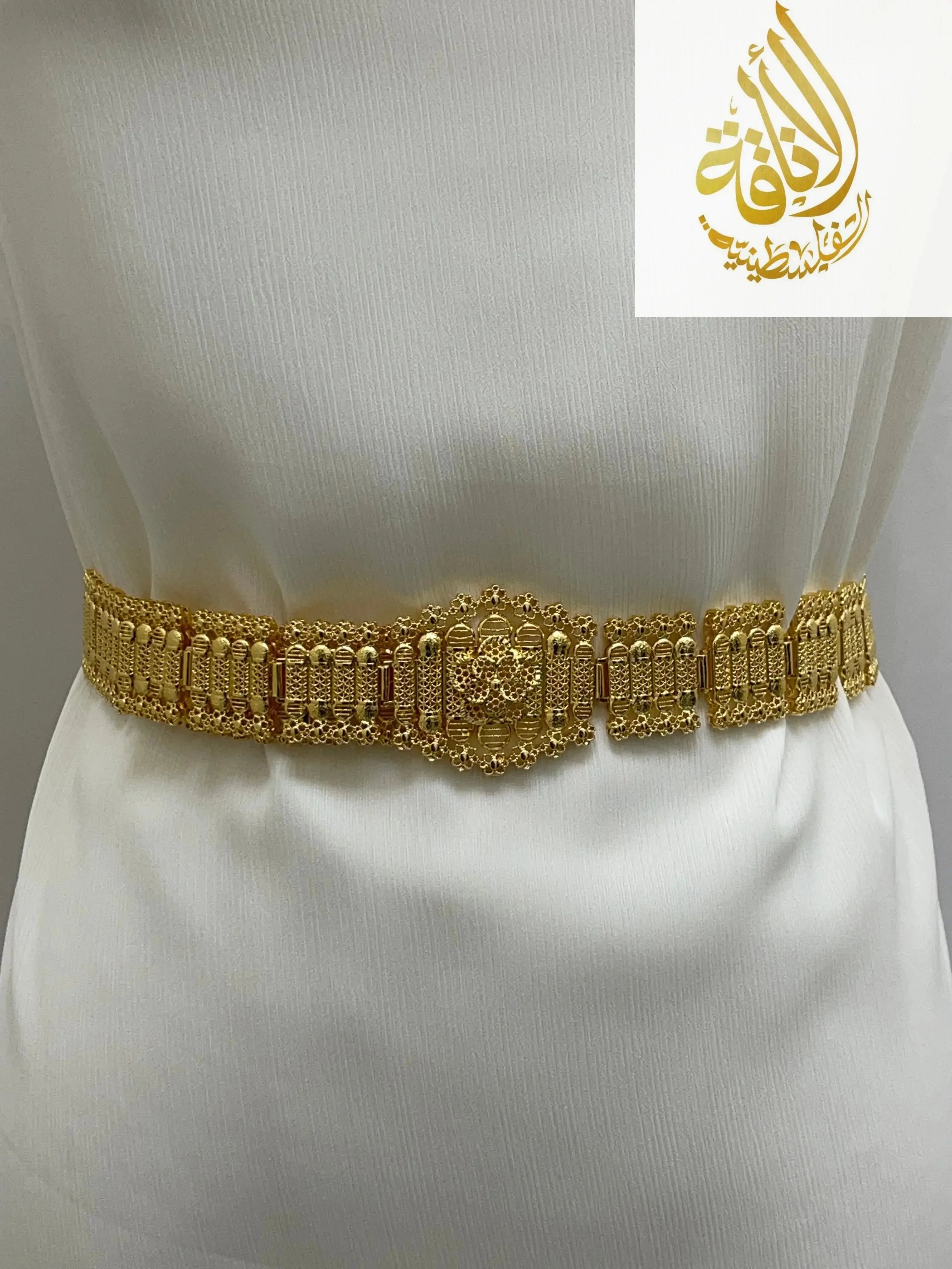 Kurdish gold style belt by Palestinian Elegance on white fabric showcasing intricate gold accessory design