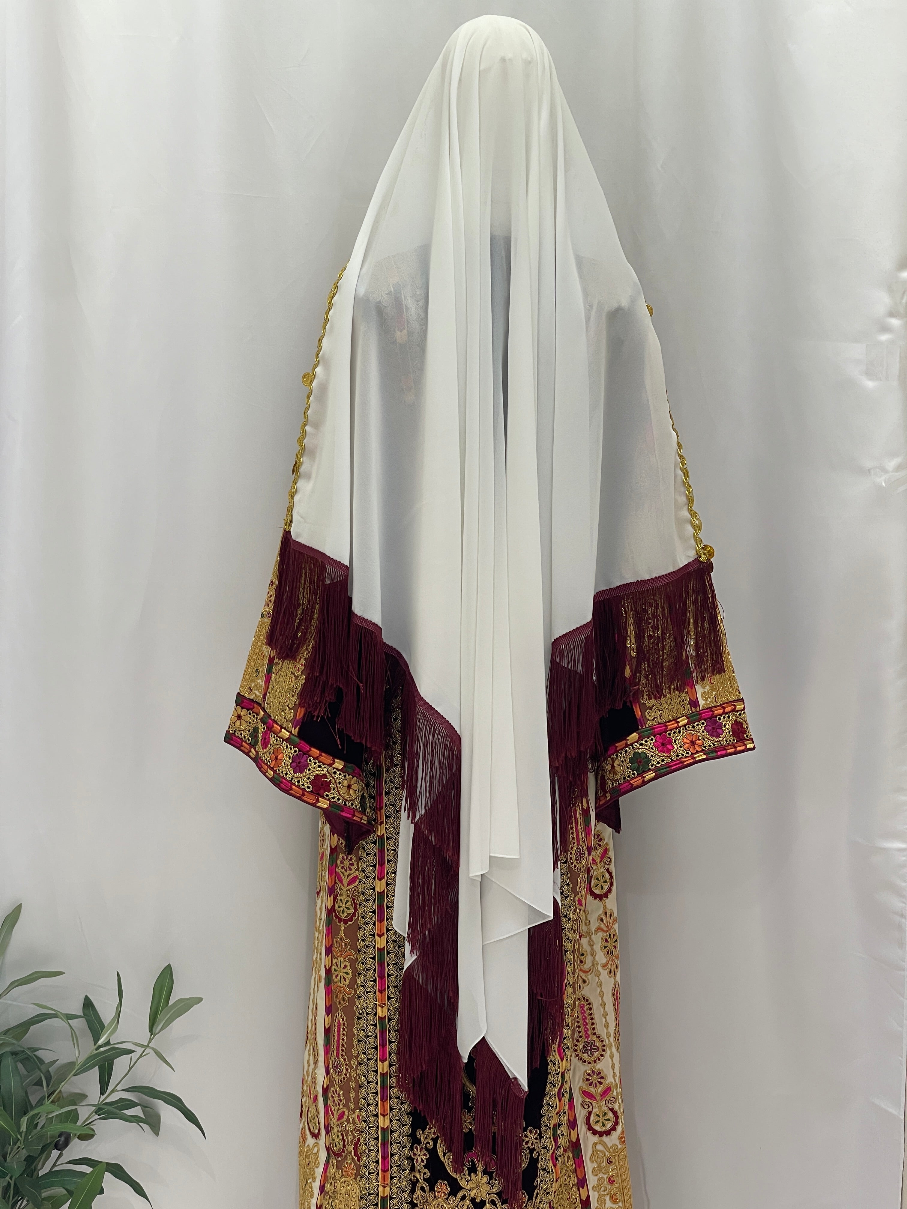 Malikat al-Turath Thoub, an embroidered thobe with intricate designs and a flowing white headscarf