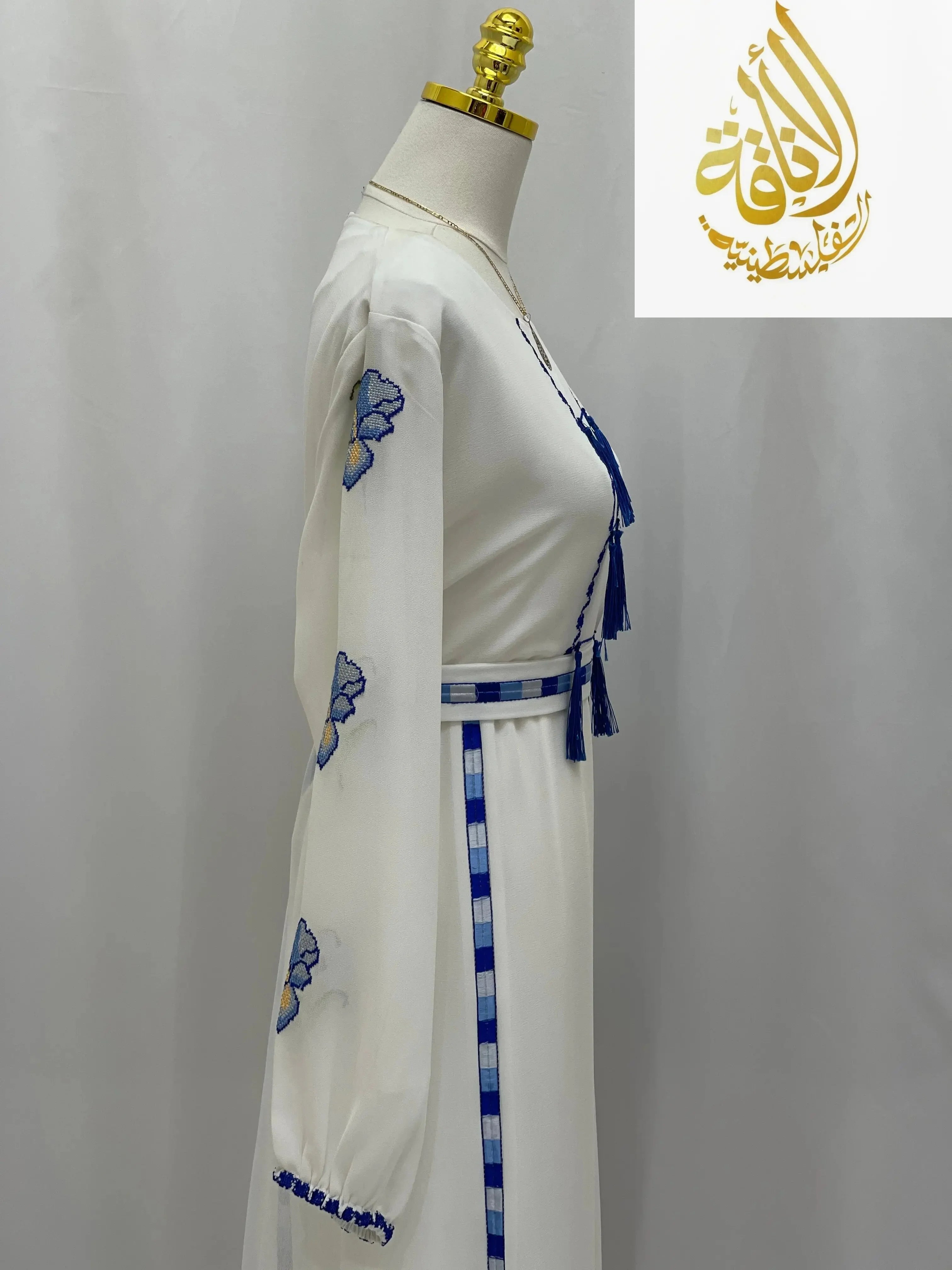 Palestinian embroidered dress in white with blue floral embroidery on sleeve and waist belt detail