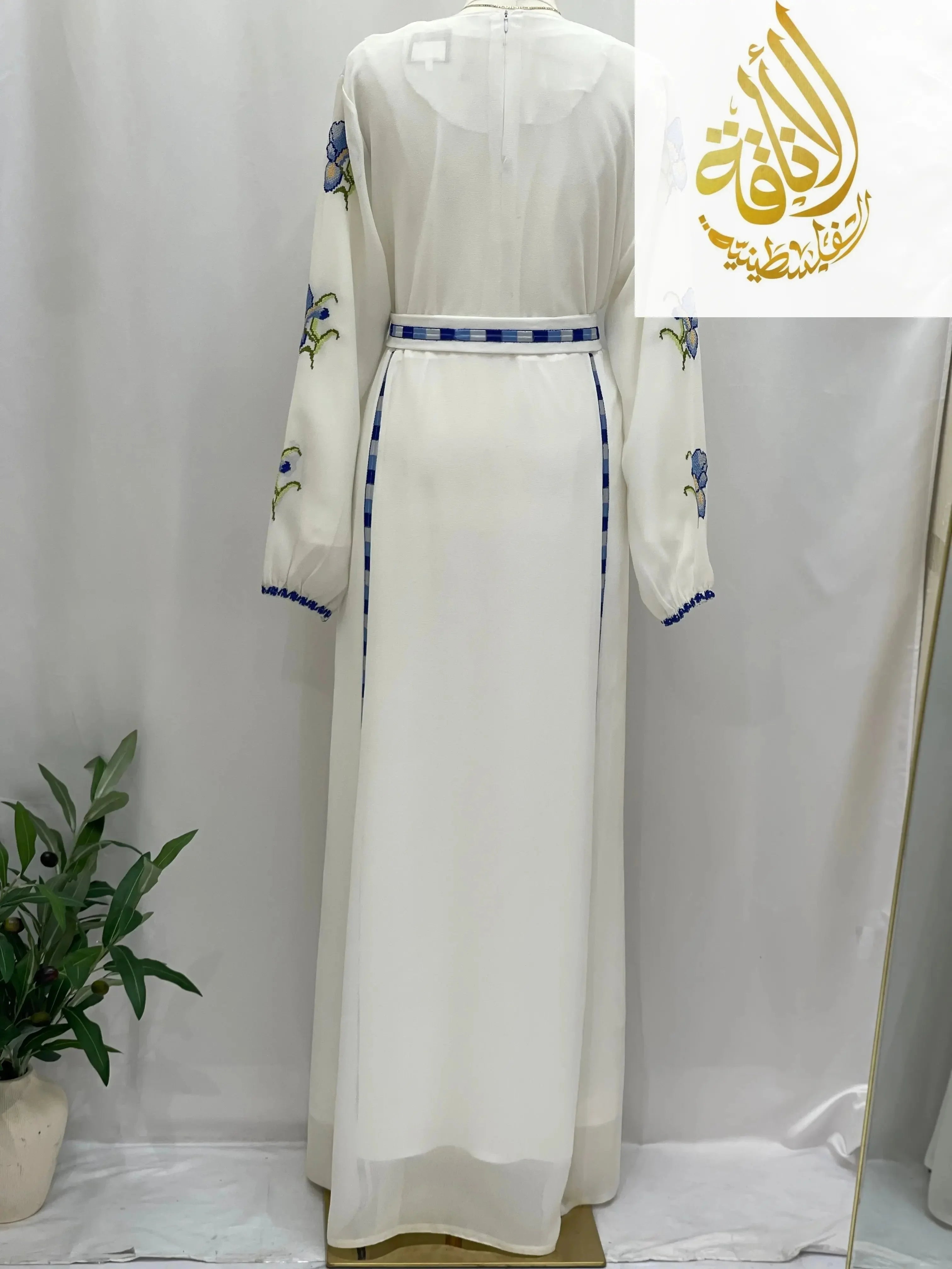 Back view of a white Palestinian embroidered dress with blue floral embroidery on sleeves and matching belt