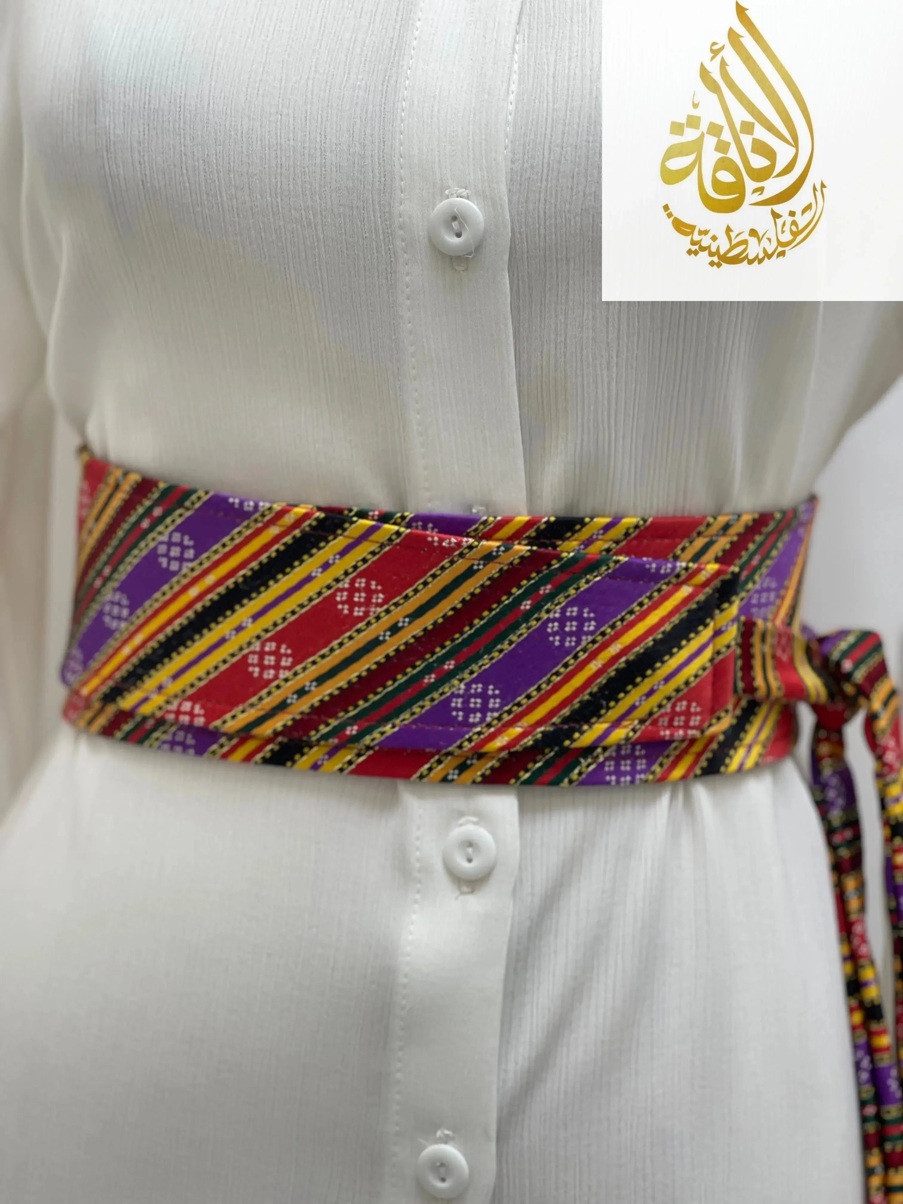Colorful Palestinian embroidered belt with traditional patterns worn over white button-up dress