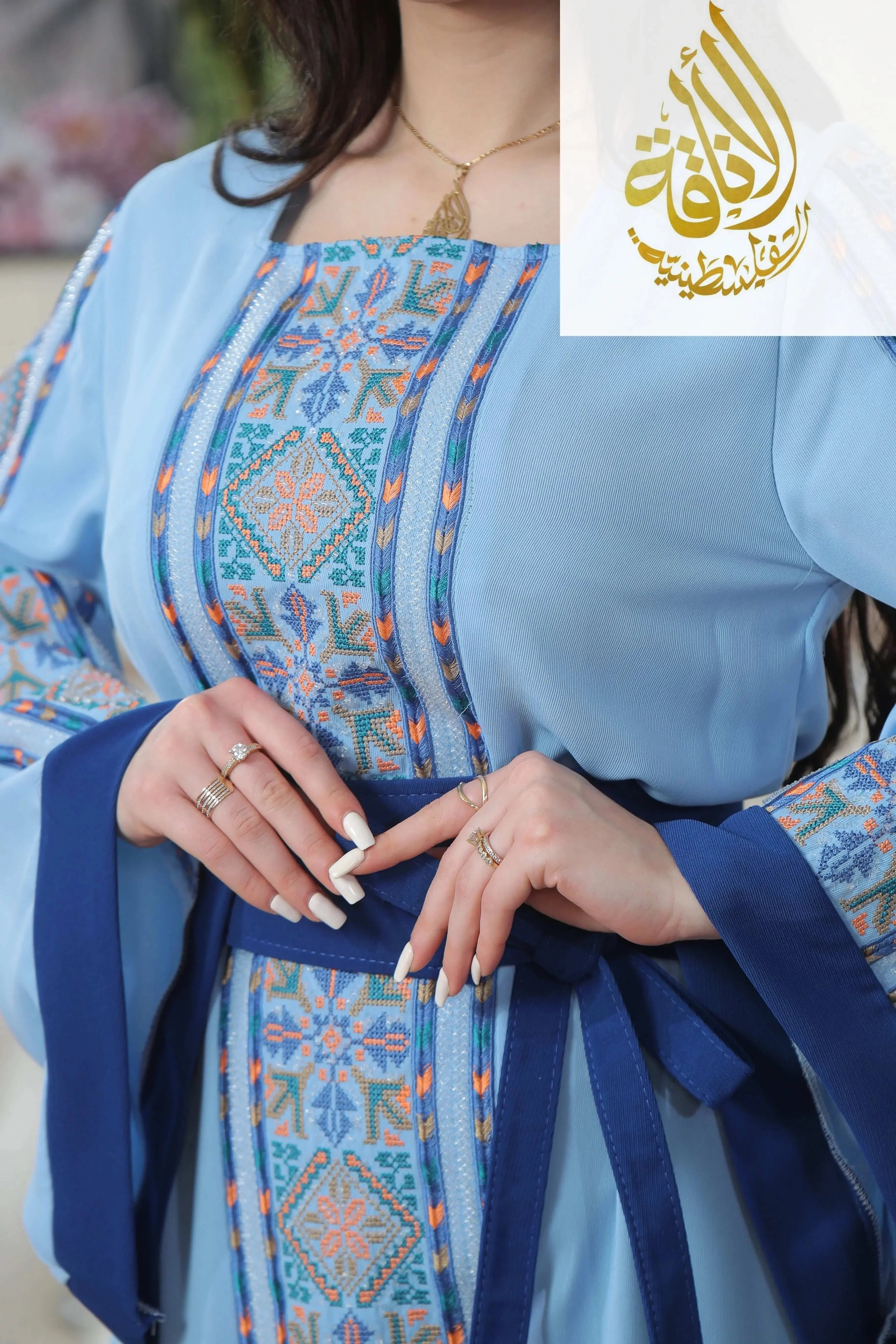 Palestinian Elegance Nadera Embroidered Thoub in light blue with intricate geometric embroidery and navy blue belt