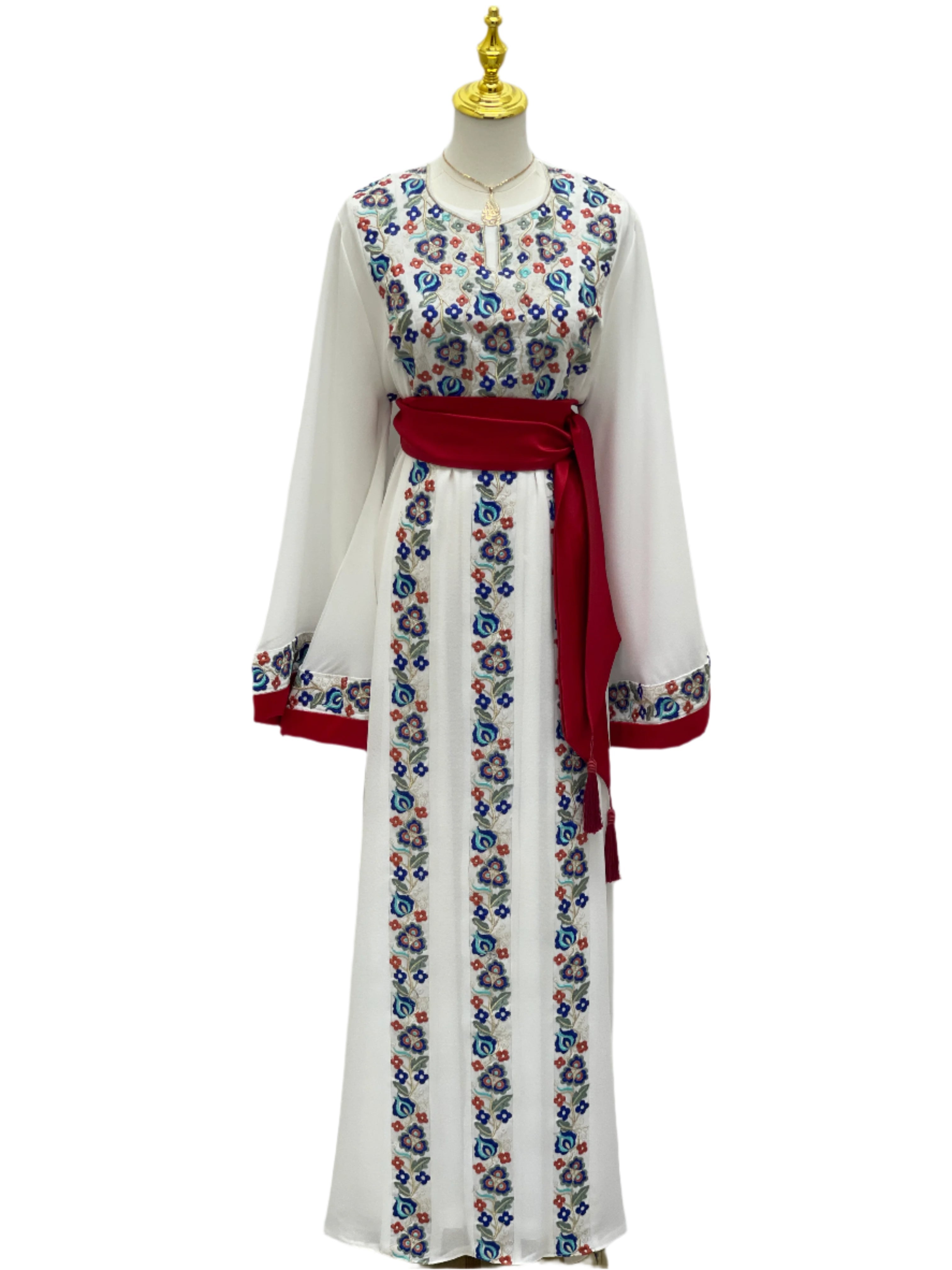 White Palestinian embroidered dress with blue and red floral patterns and red waist sash by Palestinian Elegance