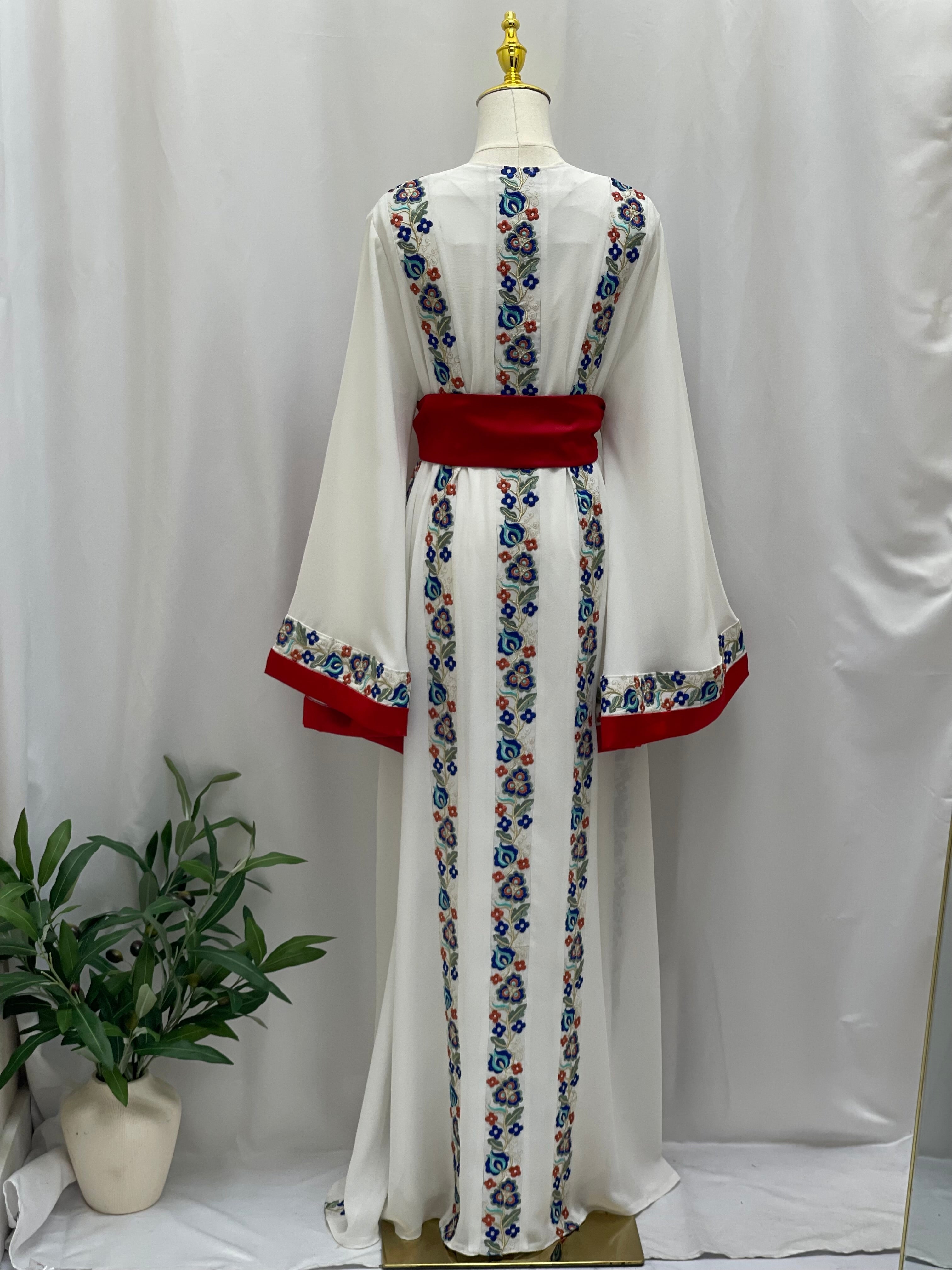 White Palestinian embroidered dress with blue and red floral embroidery and red waistband by Palestinian Elegance