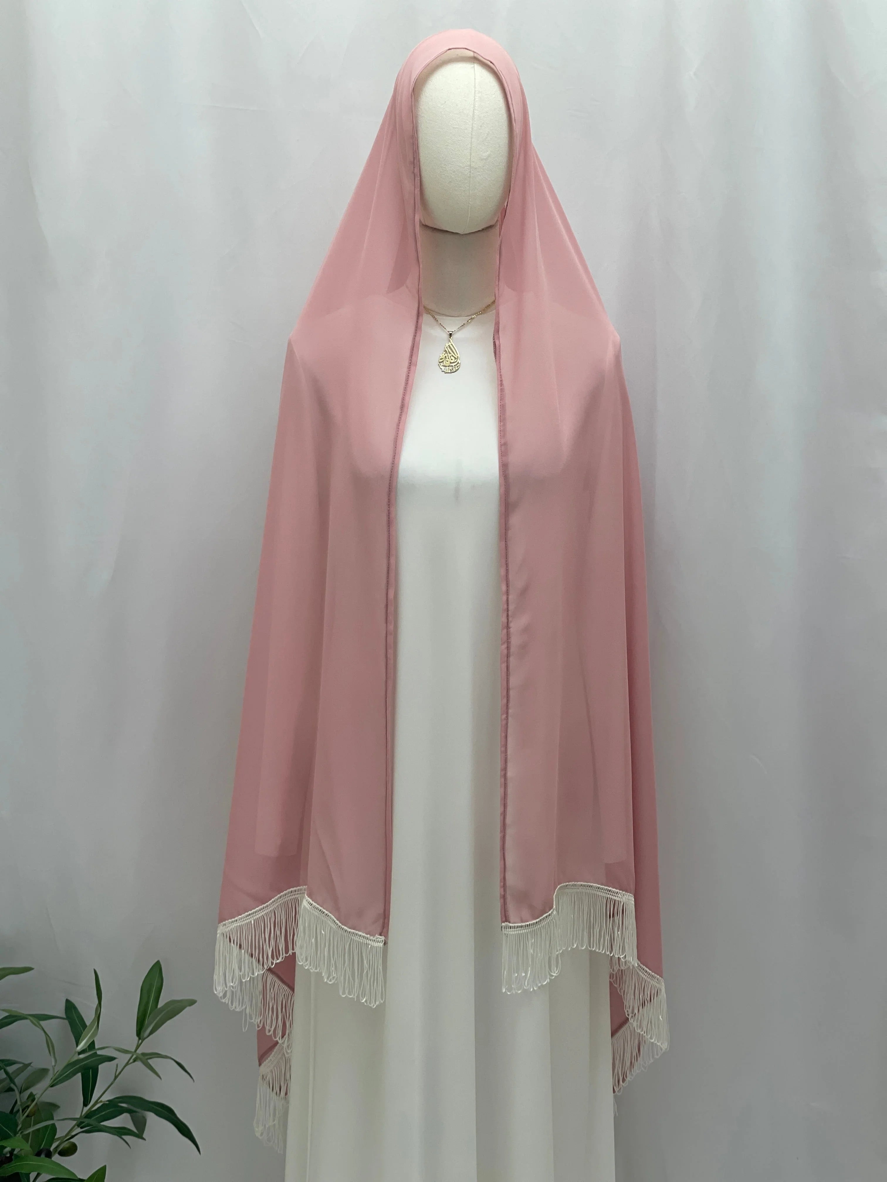 New Khirka With White tassel pink chiffon khirka draped on mannequin over white dress with fringed hem by Palestinian Elegance