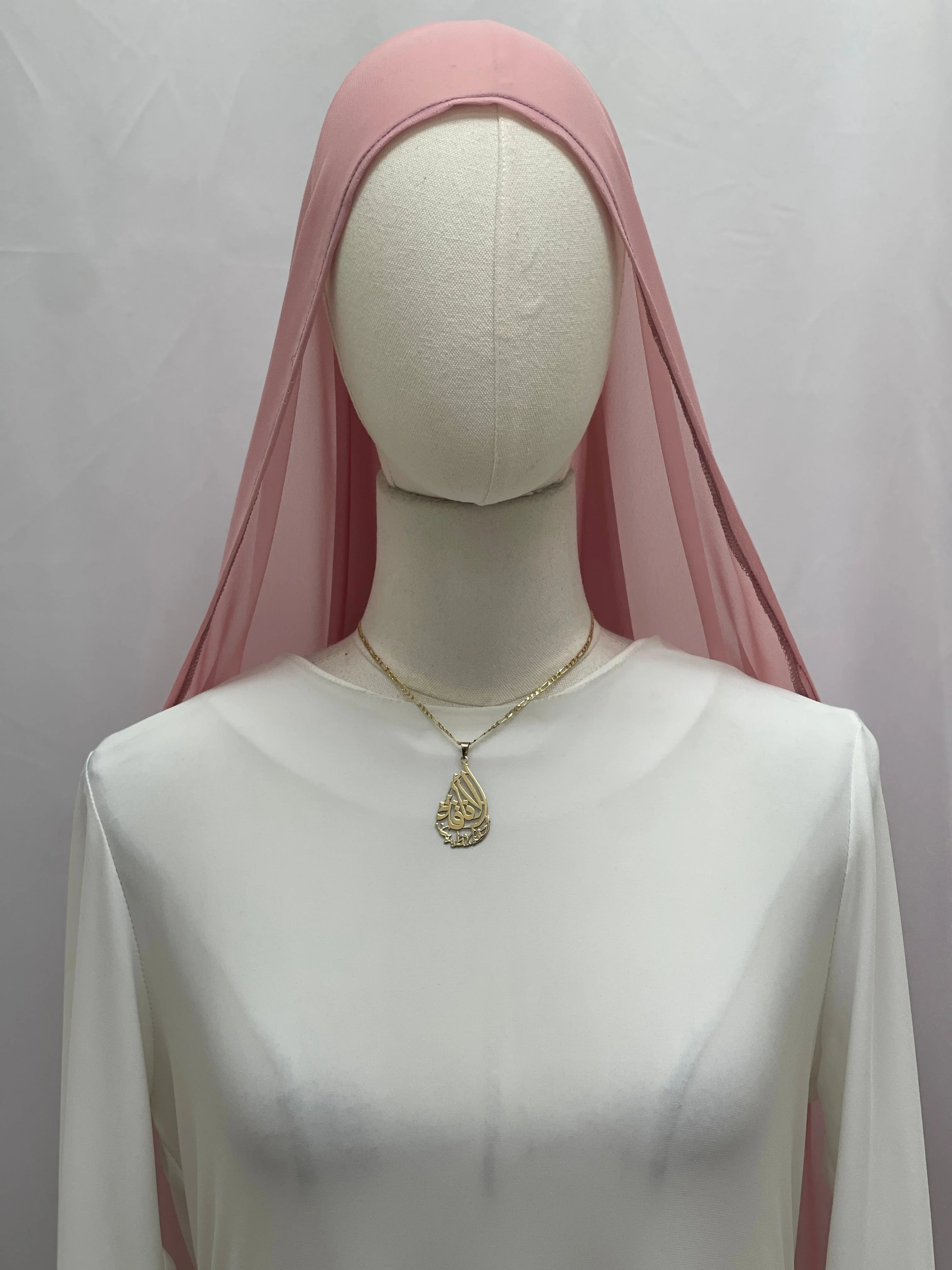 New Khirka With White tassel pink sheer head covering over white dress on mannequin with gold pendant necklace