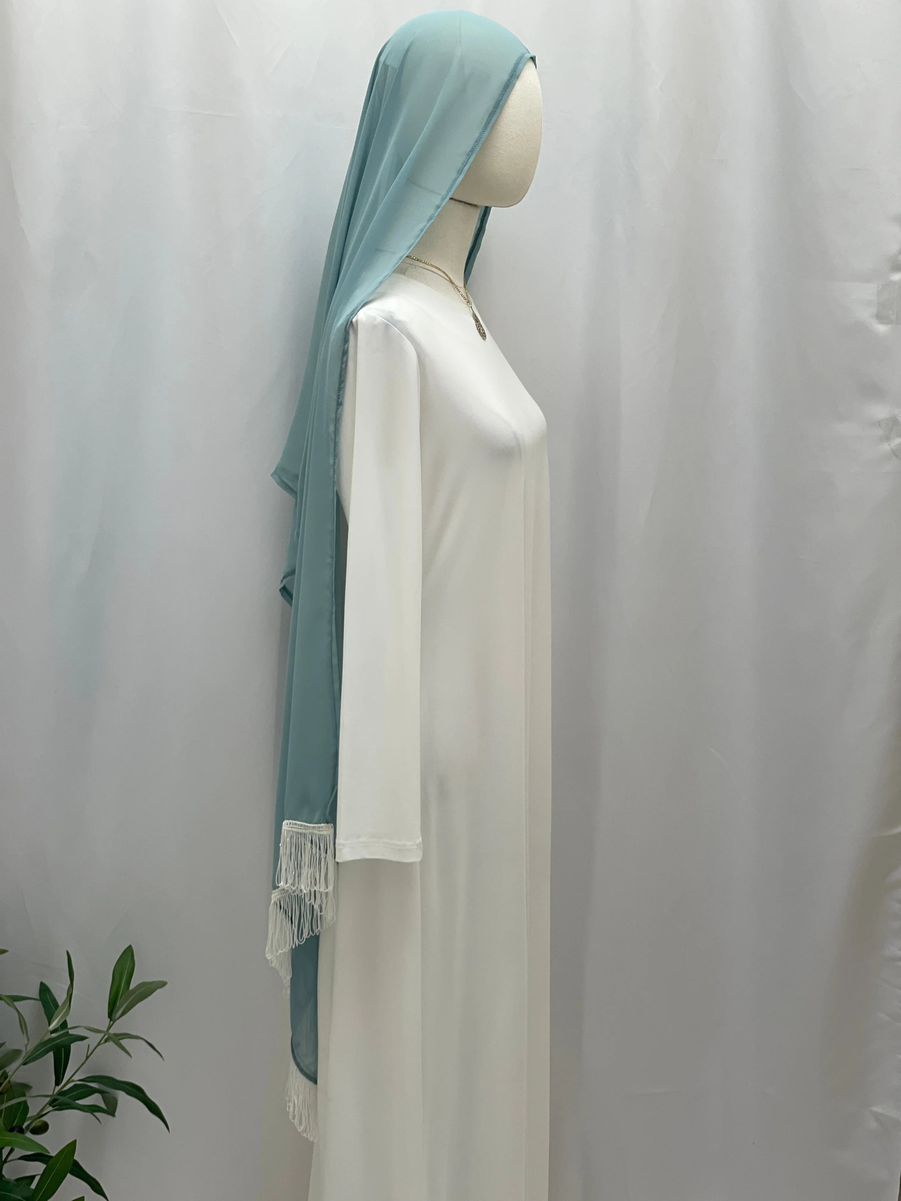 New Khirka With White tassel light blue khirka draped over white abaya on mannequin by Palestinian Elegance
