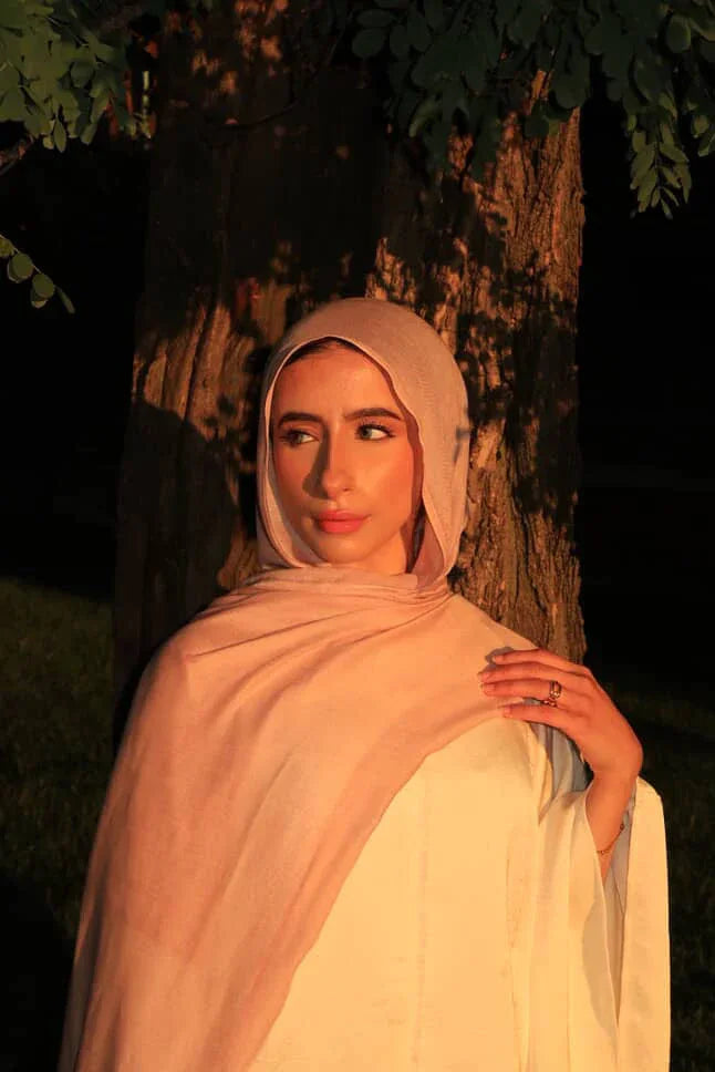 Palestinian Elegance woman wearing New Modal Hijab in soft blush pink outdoors against tree in warm light
