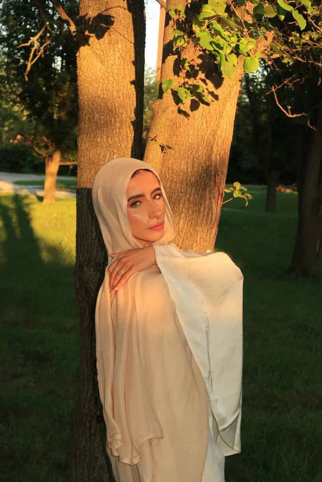 Palestinian Elegance New Modal Hijab cream beige draped on model leaning against tree in golden hour
