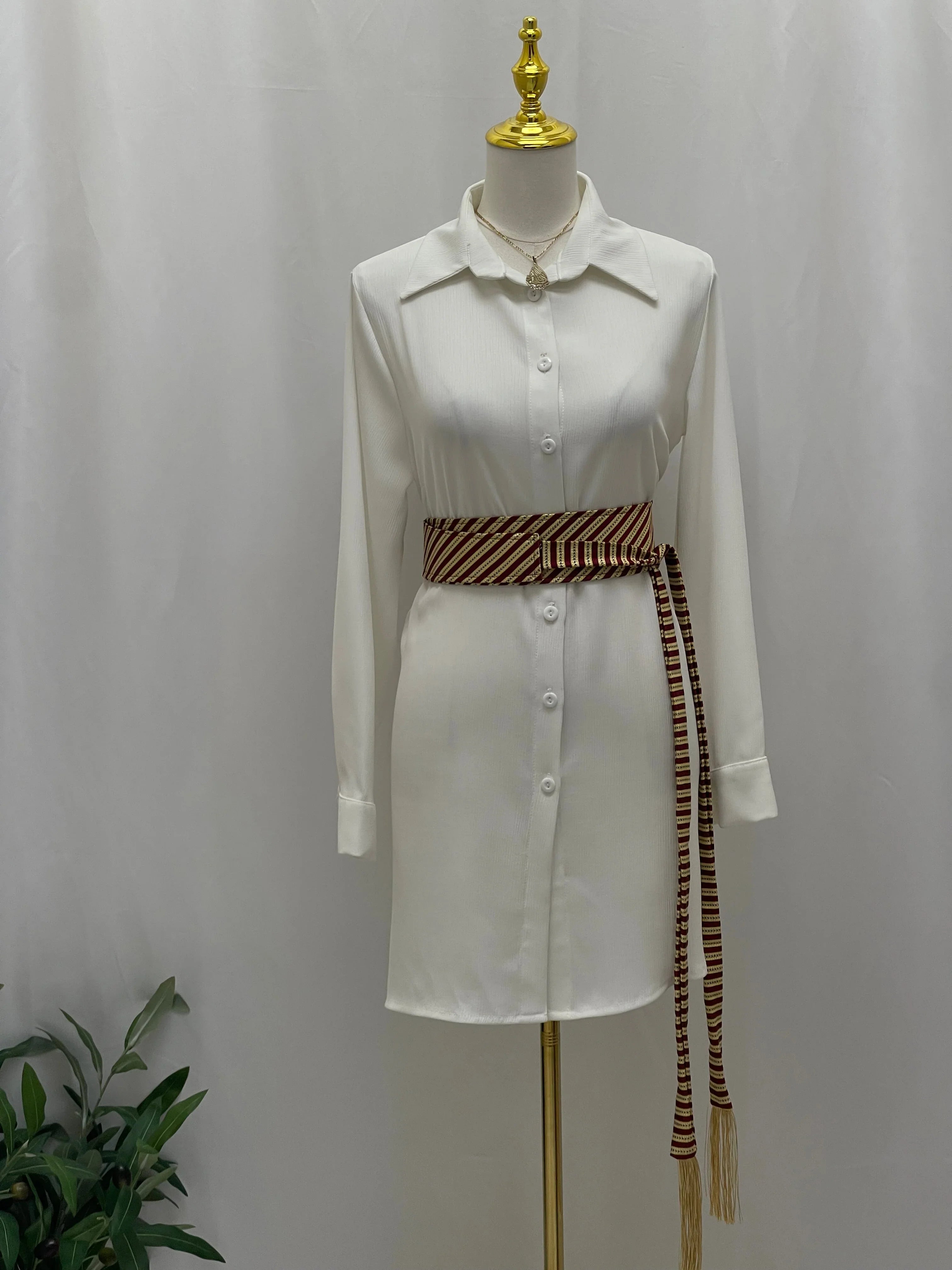 Saya Belt by Palestinian Elegance brown striped woven sash belt with long tassels on white shirt dress