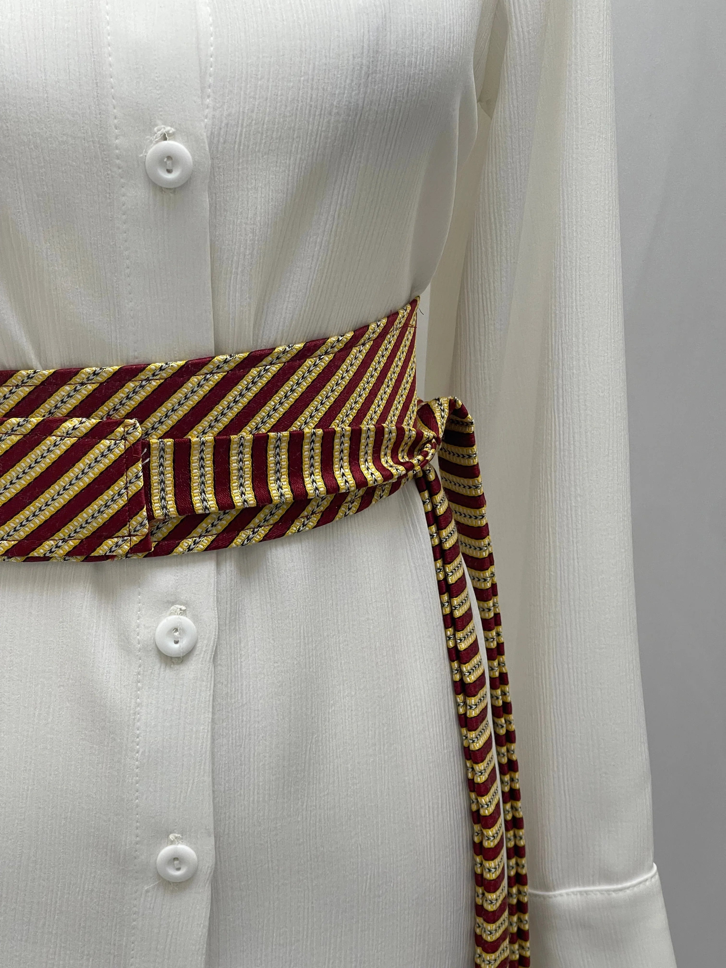 Palestinian Elegance Saya Belt maroon and gold striped woven obi belt tied over white dress