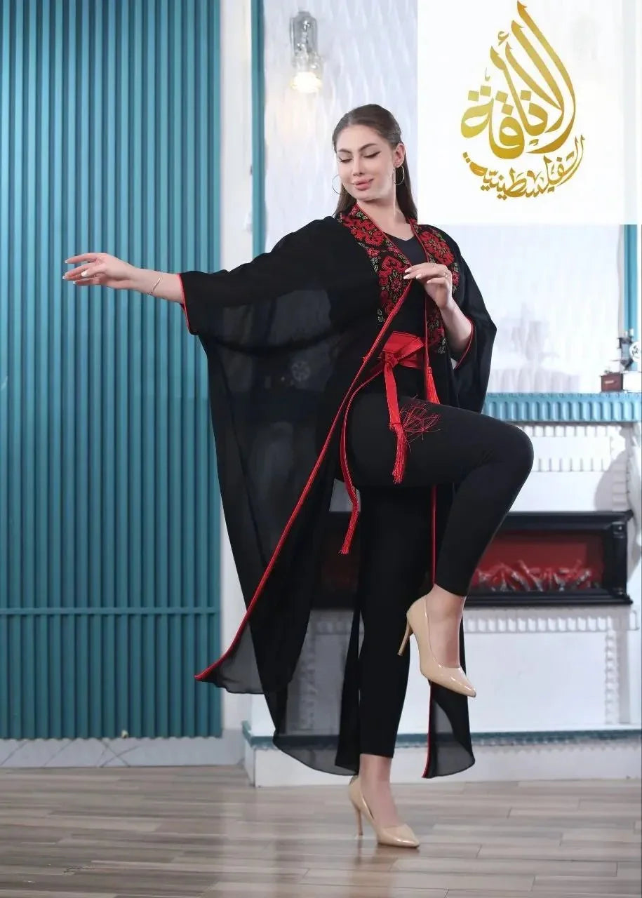 Black embroidered bisht for women with red detailing by Palestinian Elegance worn with black pants and beige heels