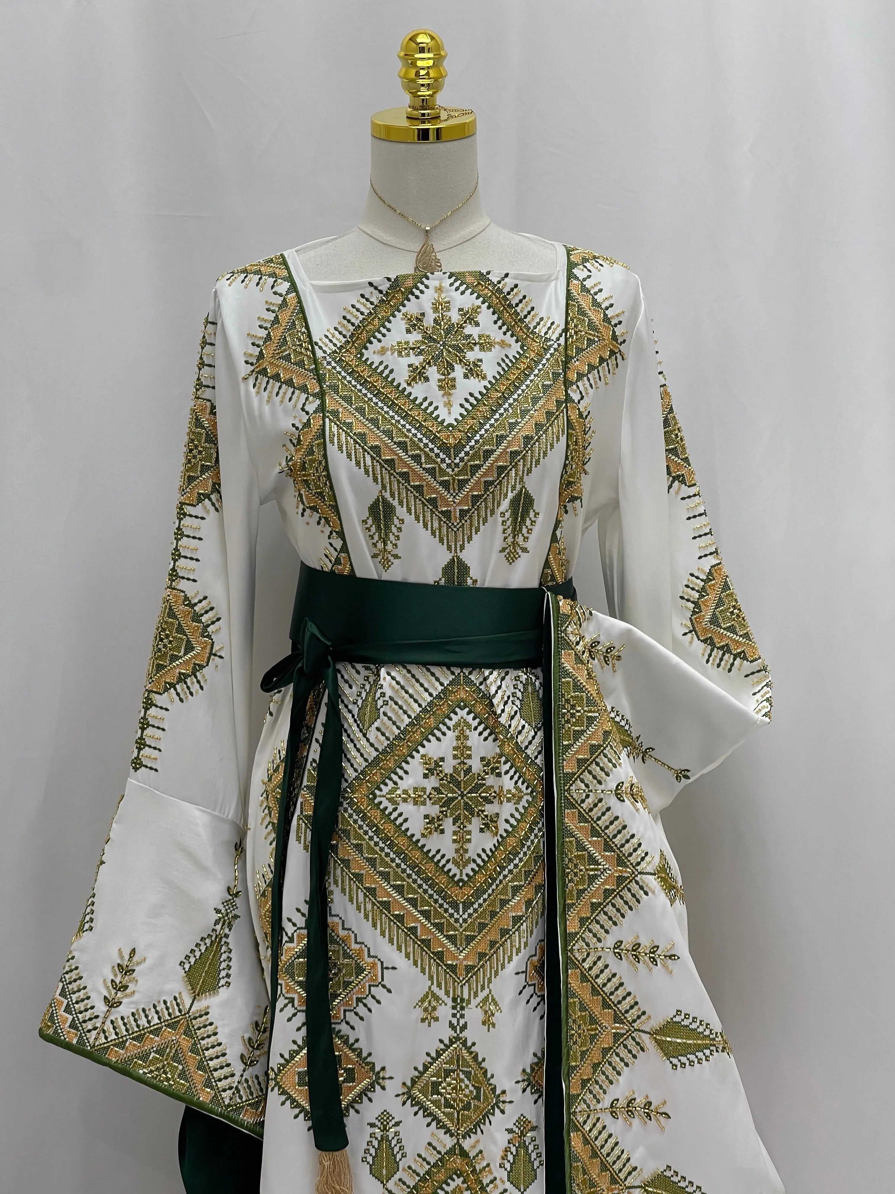 Olive Bloom Bridal Embroidered Dress by Palestinian Elegance white gown with green gold Palestinian embroidery and sash belt