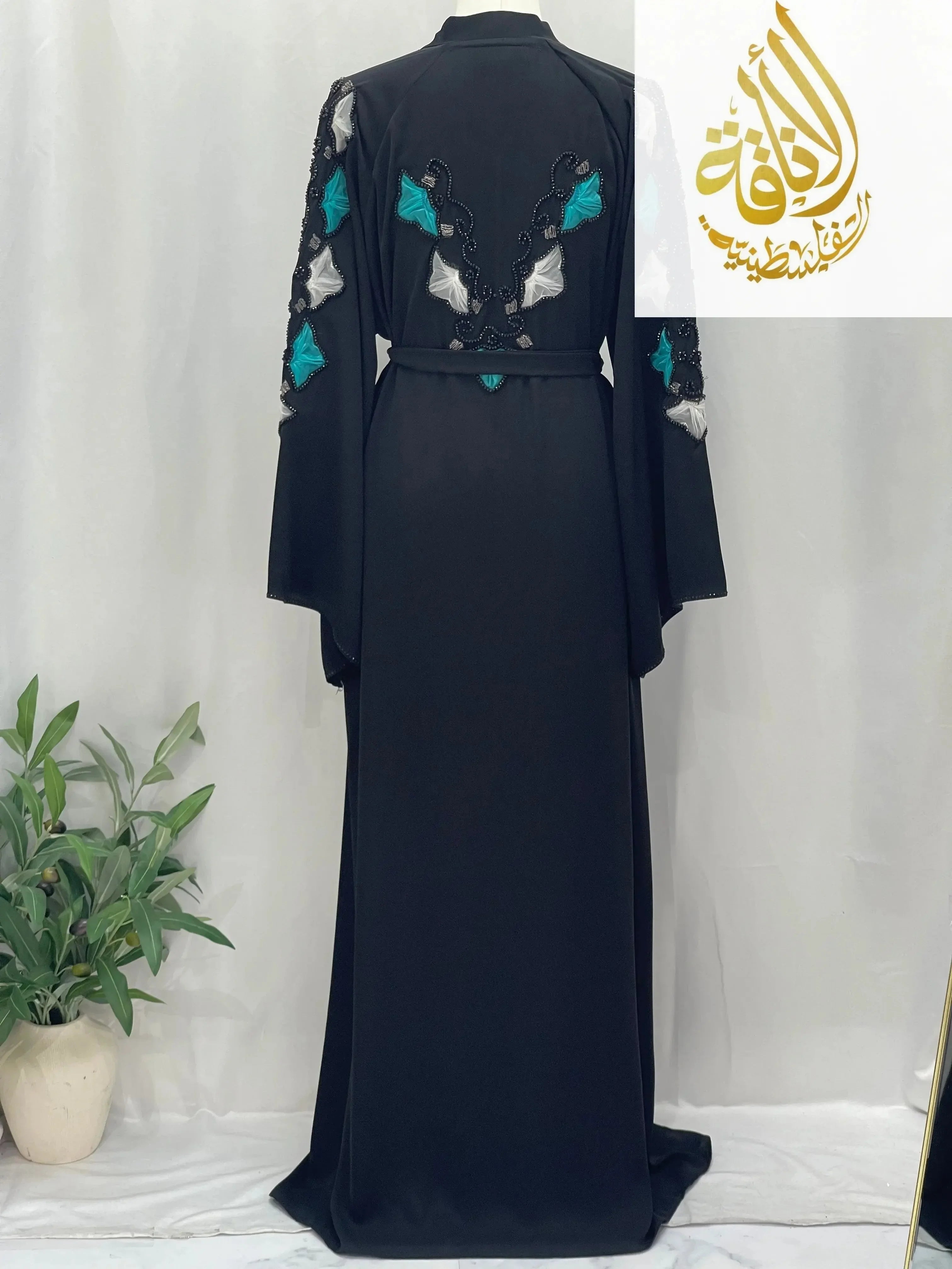 Elegant black abaya from Palestinian Elegance with intricate turquoise and white embroidery on the back and sleeves