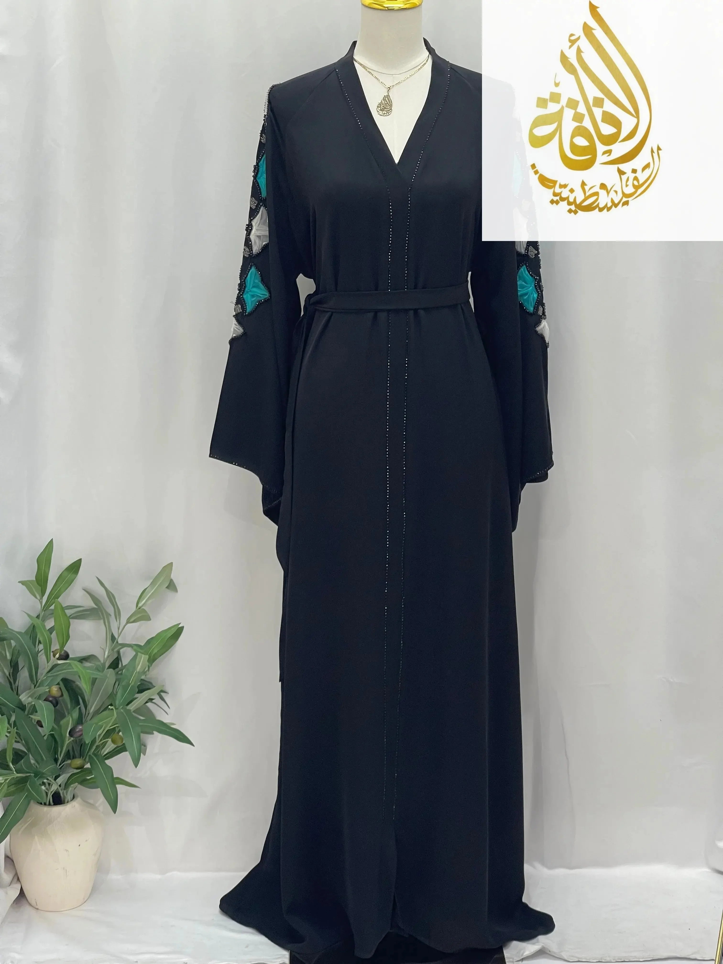 Elegant black abaya by Palestinian Elegance with embroidered teal and white floral sleeves and waist belt