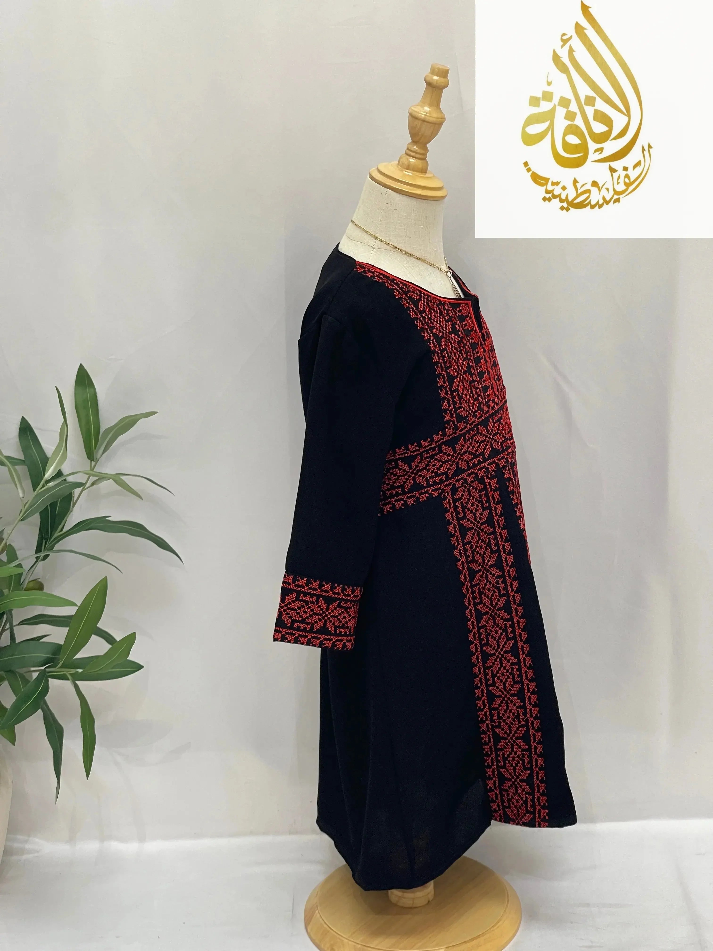 Kid's black dress with red embroidery titled Haya Embroidered Abaya by Palestinian Elegance on mannequin