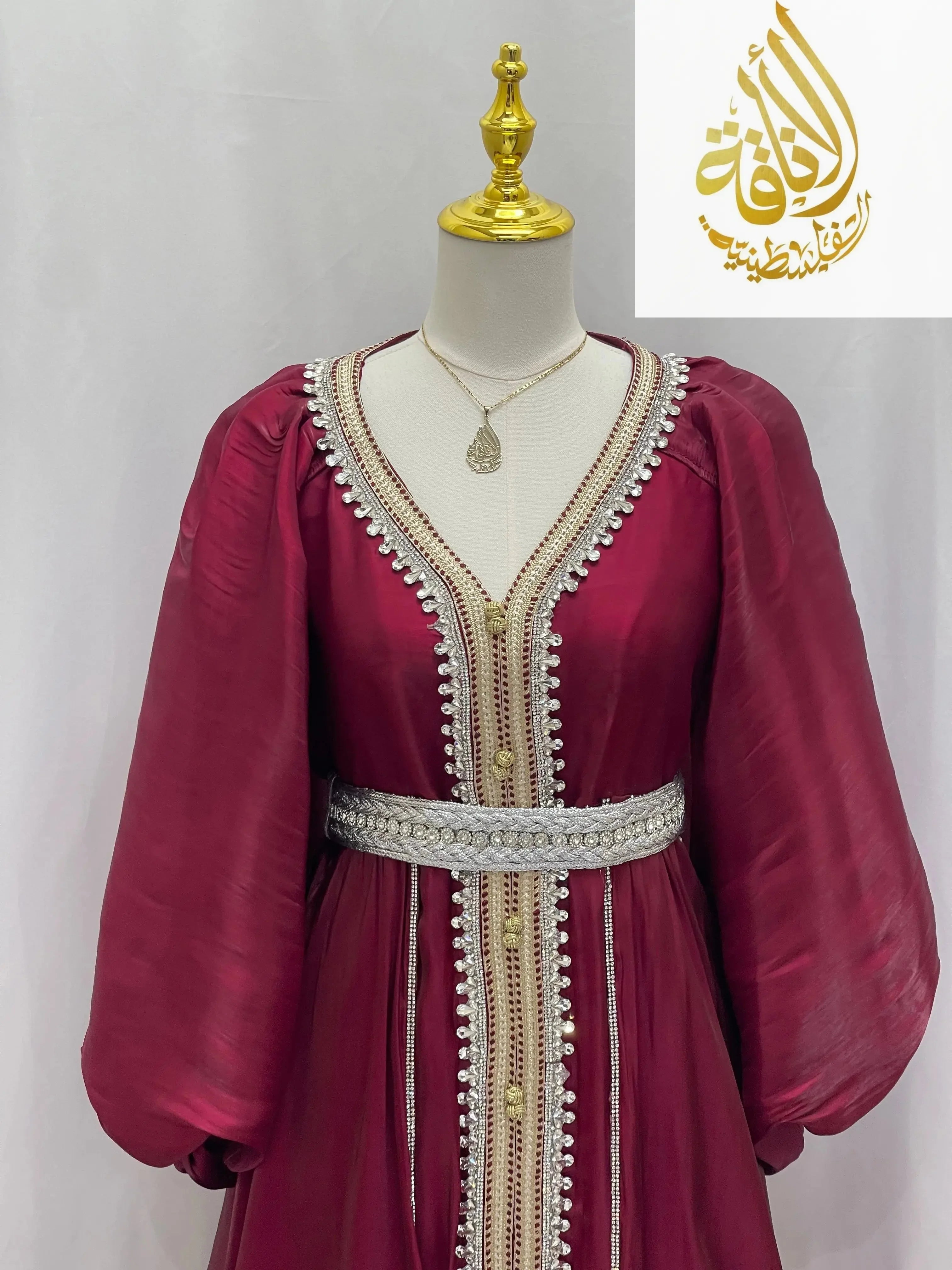 Palestinian Elegance maroon puffy sleeves kaftan dress with intricate gold and white embroidery and a decorative belt