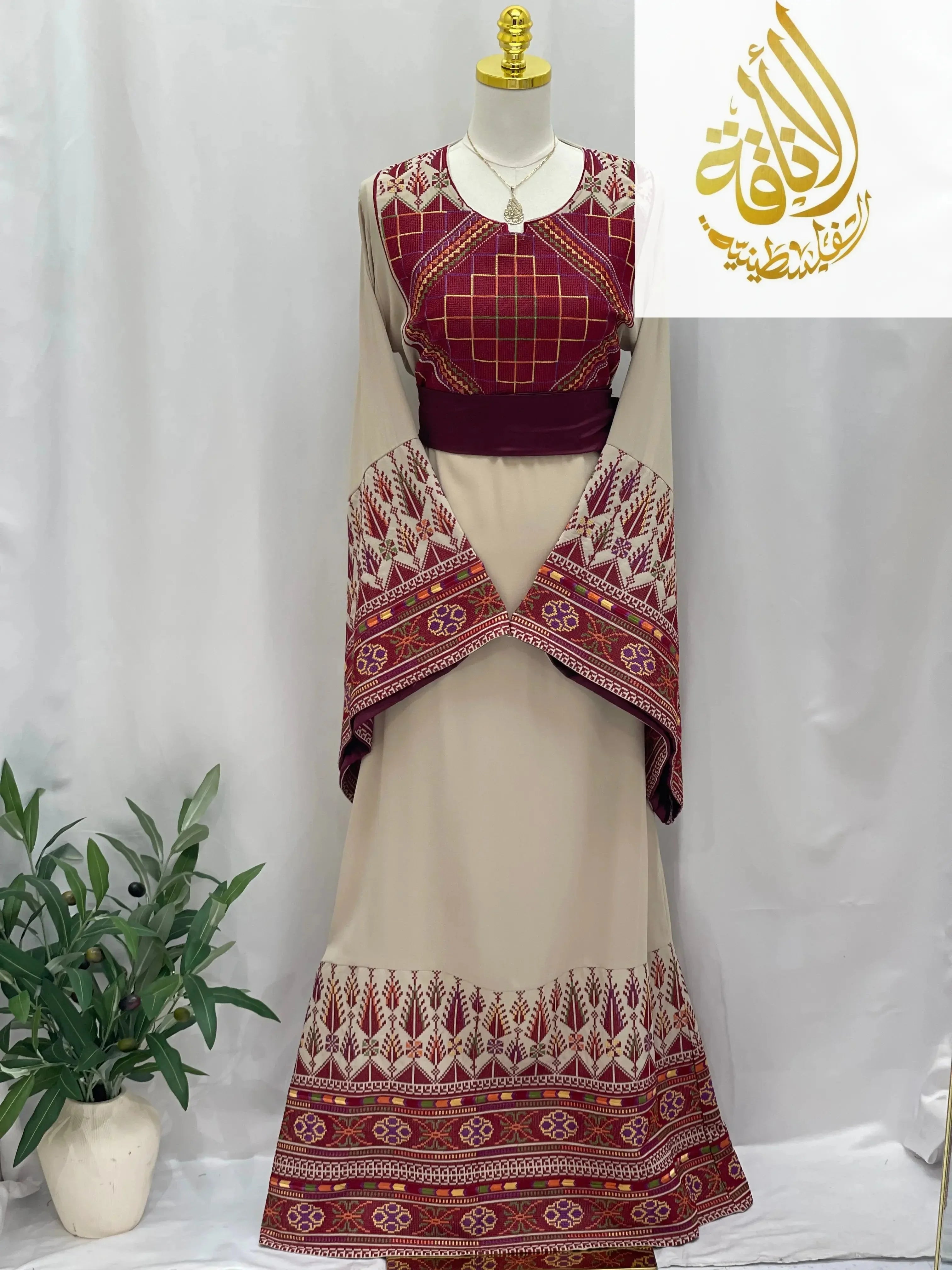 Randa Embroidered Thoub by Palestinian Elegance with detailed maroon embroidery on beige fabric and wide sleeves