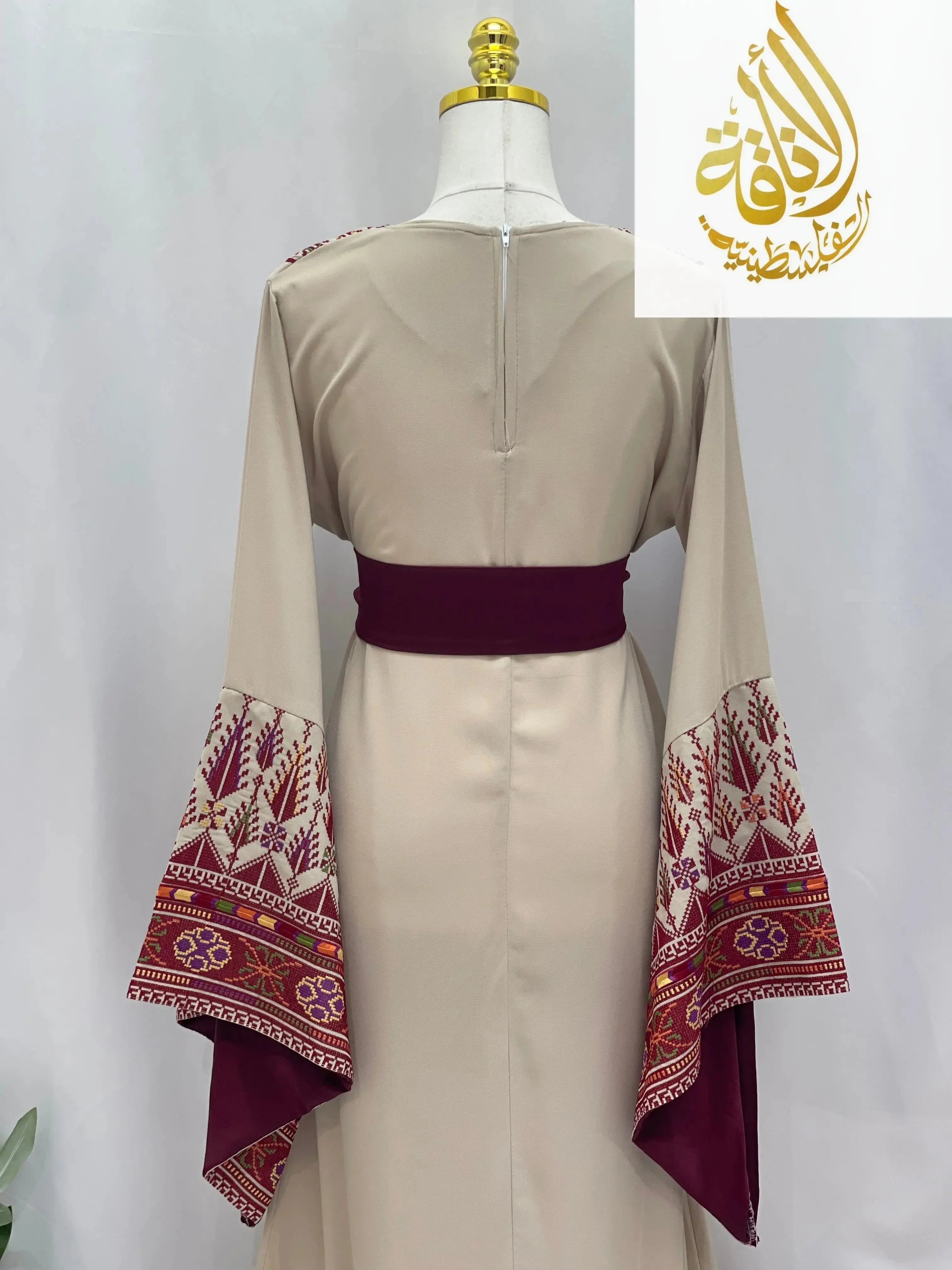 Back view of Randa Embroidered Thoub by Palestinian Elegance with beige fabric and detailed maroon embroidery on wide sleeves