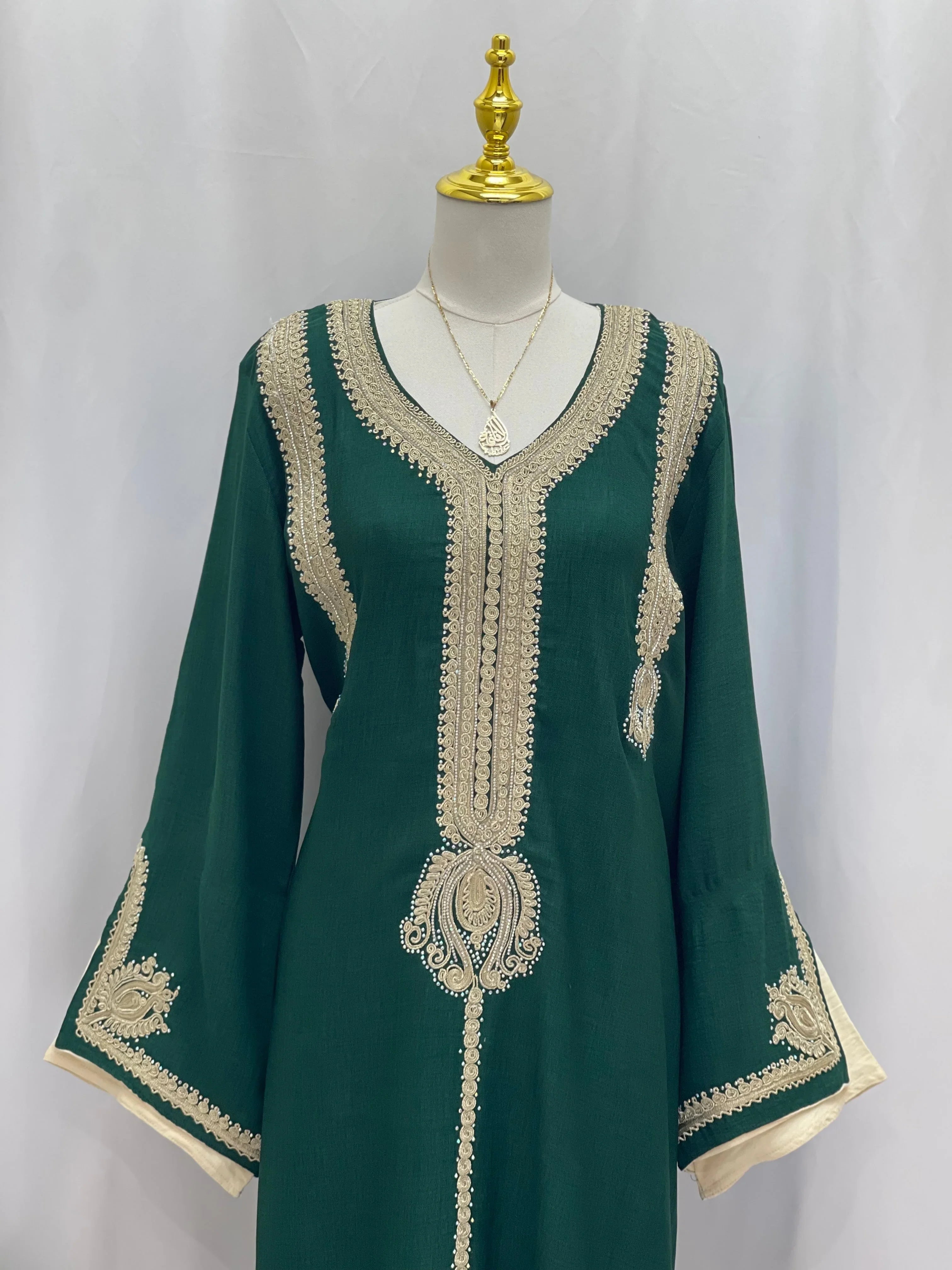 Green embroidered Regal Moroccan Jalabiya by Palestinian Elegance on mannequin with gold lace V neck and bell sleeves