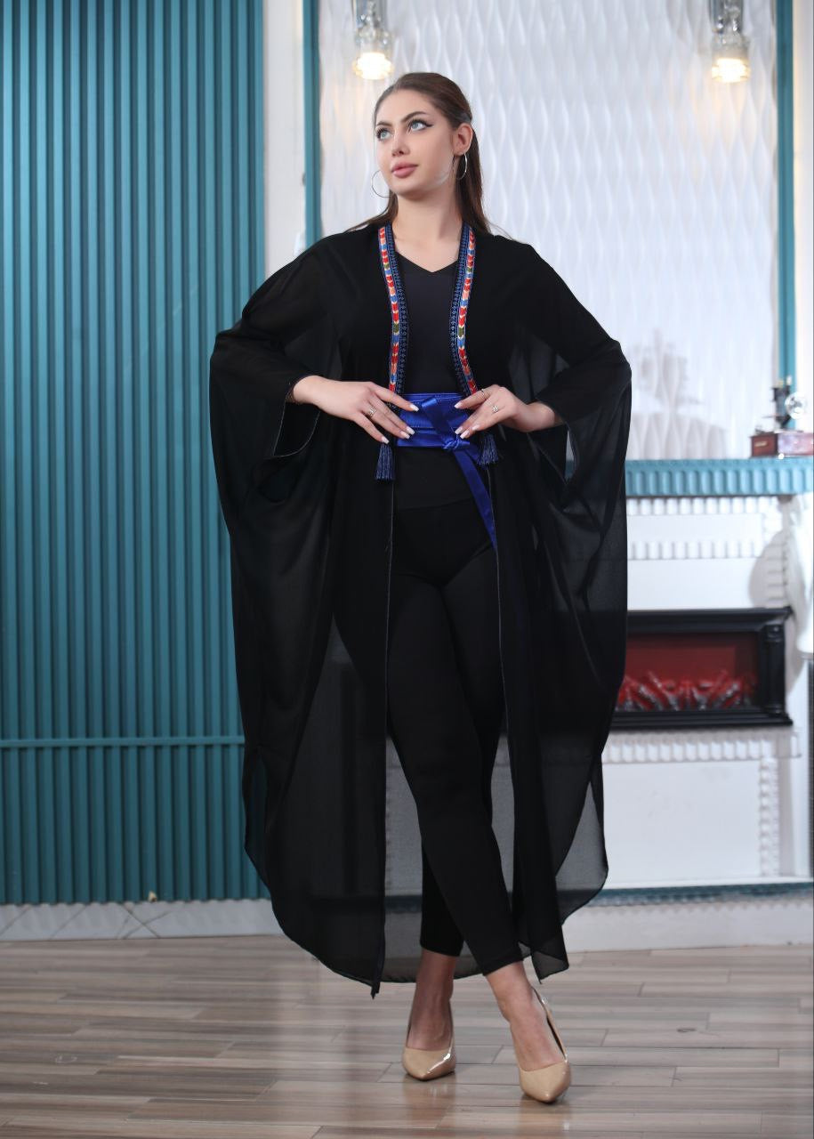 Black embroidered chiffon cardigan by Palestinian Elegance worn over black outfit with blue belt