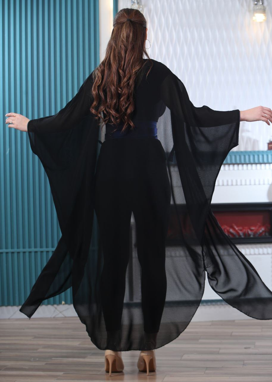 Back view of woman wearing black embroidered chiffon cardigan by Palestinian Elegance with flowing sheer fabric