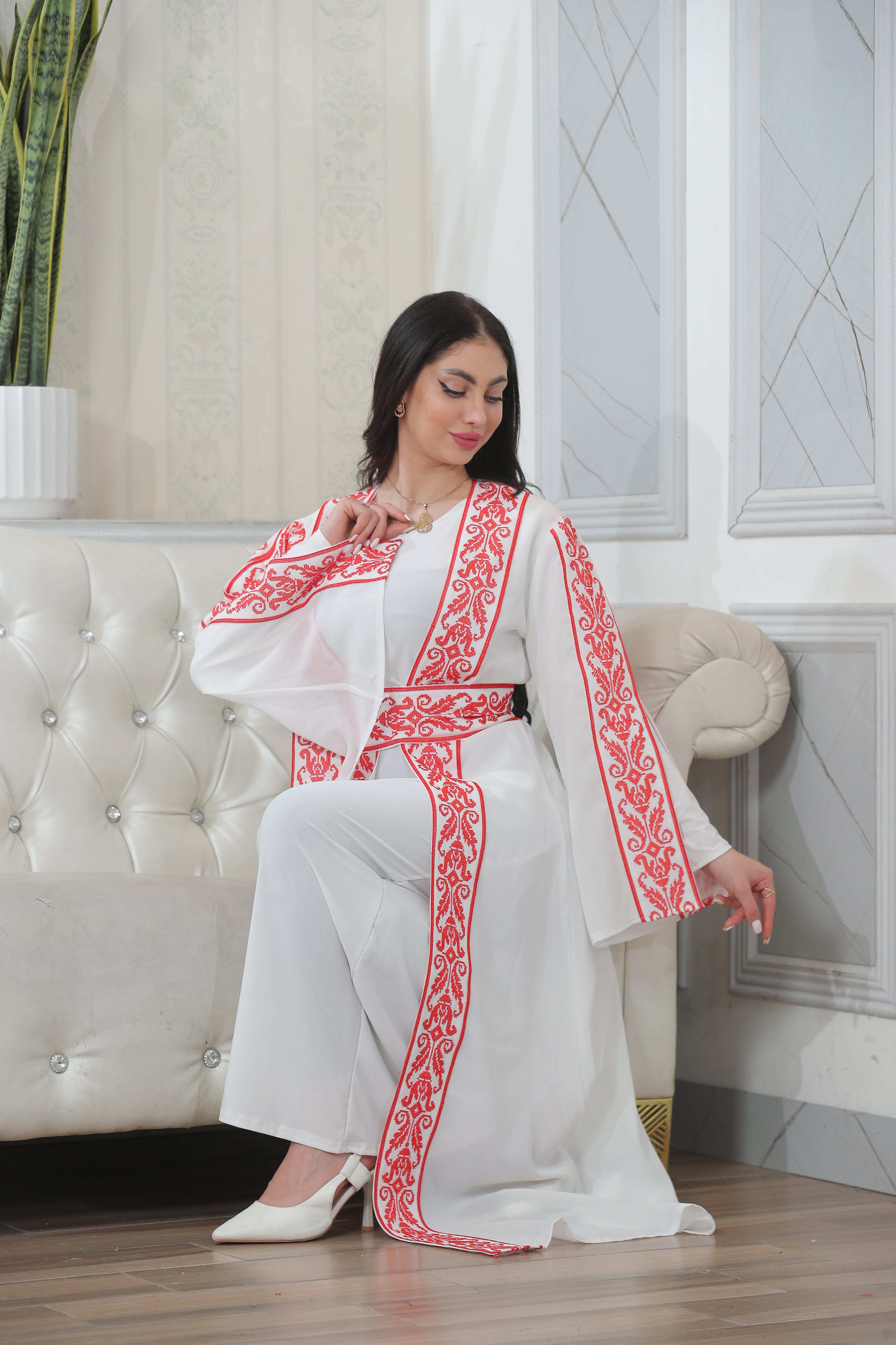 Woman wearing Shereen Embroidered Bisht Abaya by Palestinian Elegance with red embroidery on white fabric