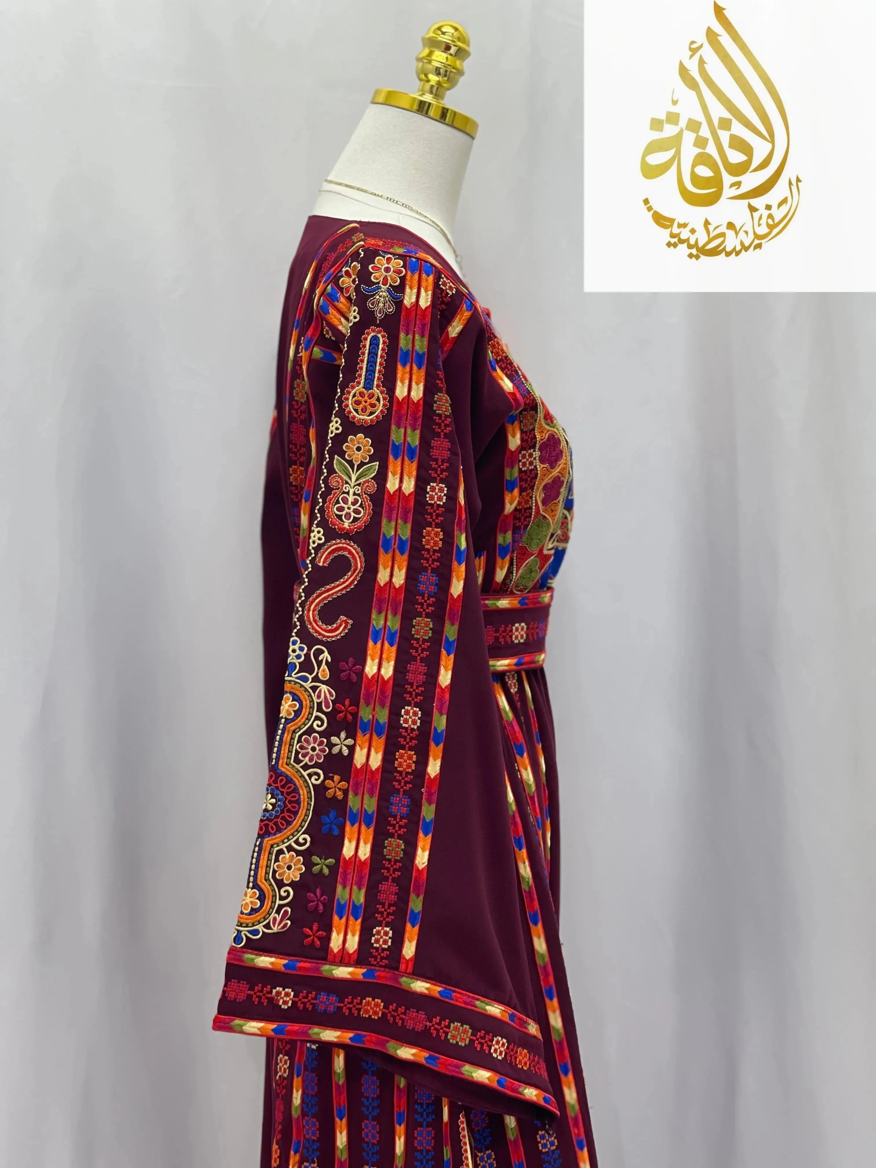 Embroidered Palestinian dress with colorful traditional patterns displayed on mannequin side view