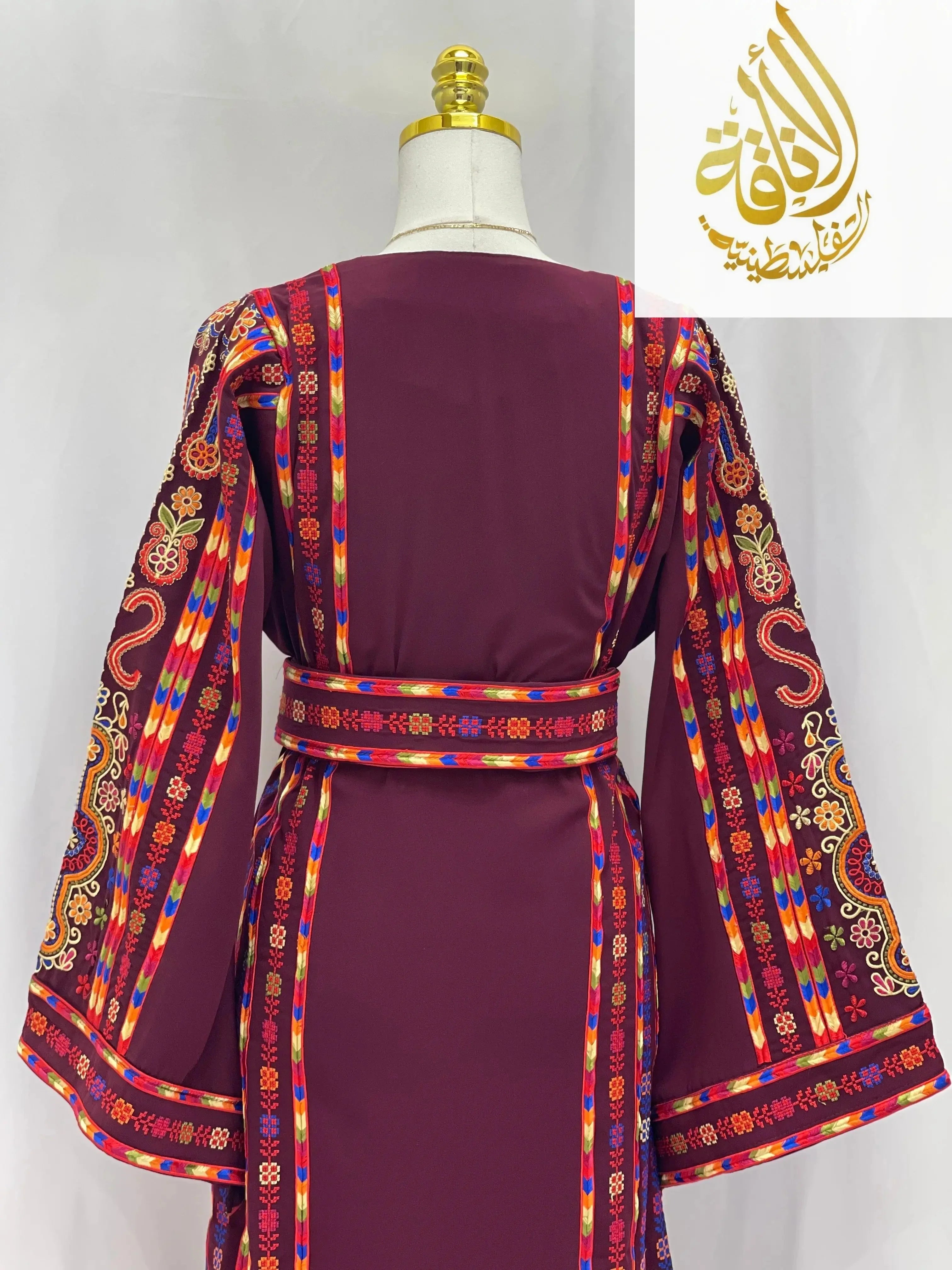 Back view of an embroidered Palestinian dress in deep maroon with colorful intricate sleeve and belt embroidery by Palestinian Elegance