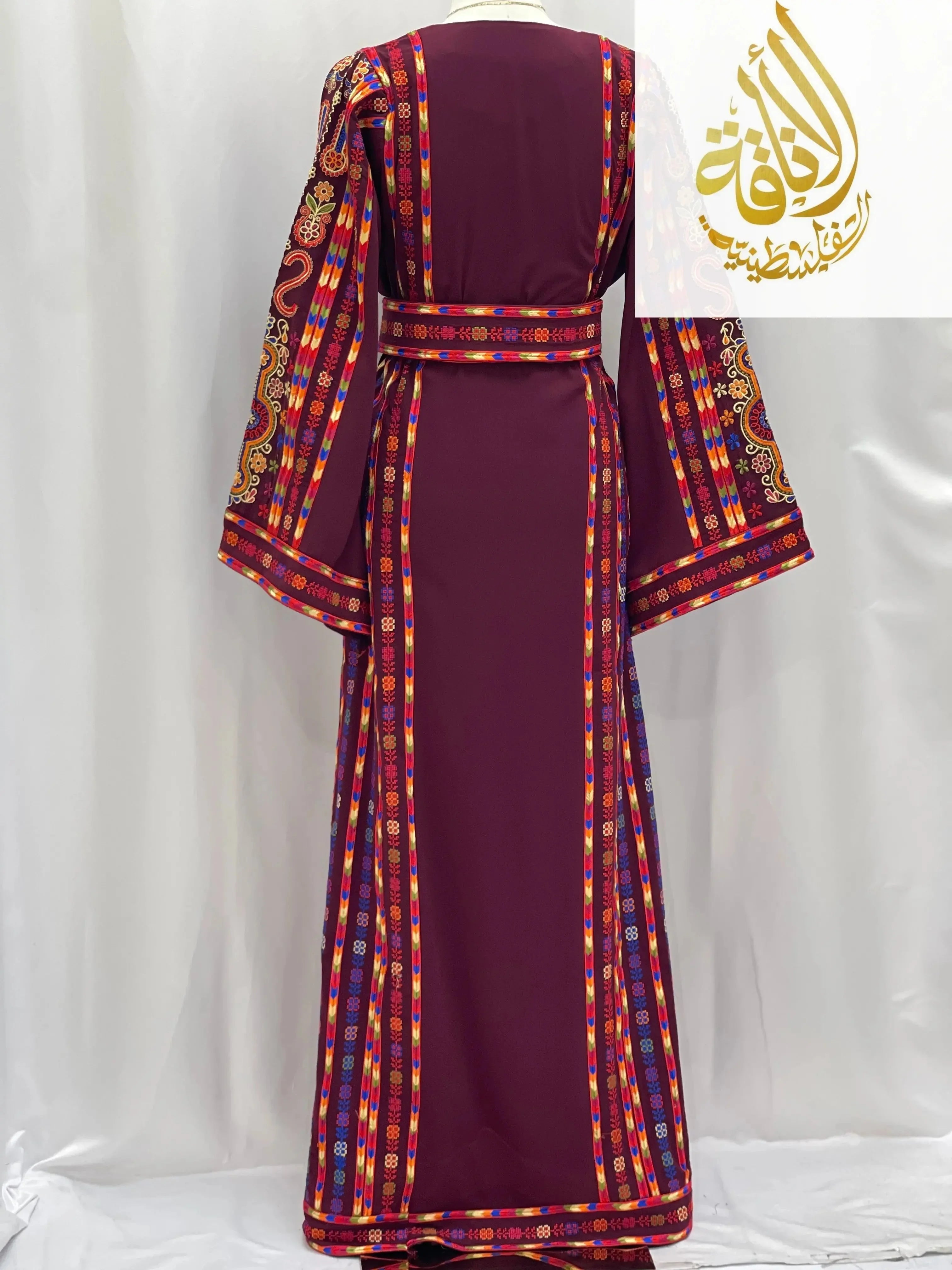 Back view of a maroon embroidered Palestinian dress with colorful intricate sleeve and belt designs