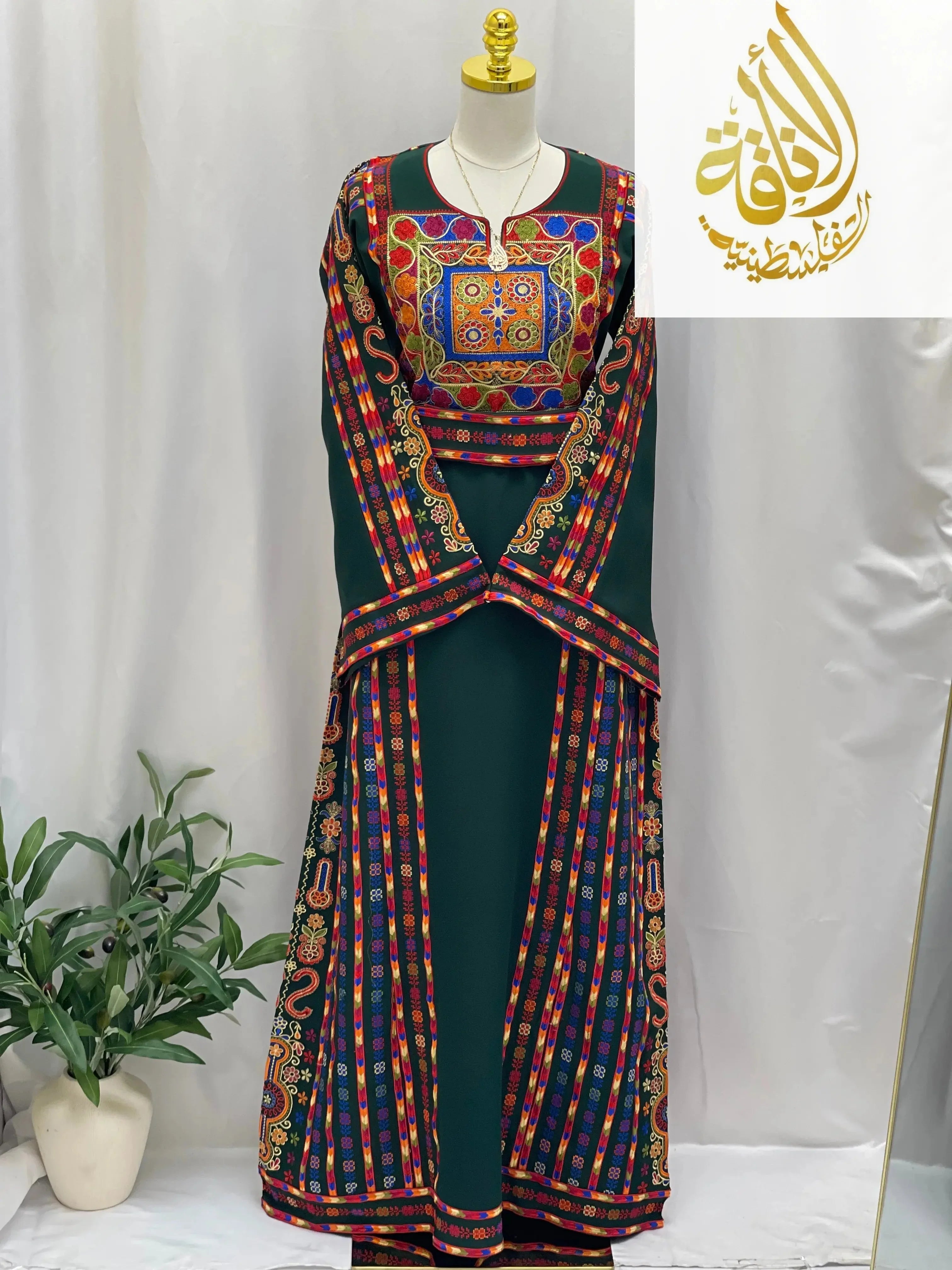 Embroidered Palestinian dress with colorful traditional embroidery by Palestinian Elegance on green fabric
