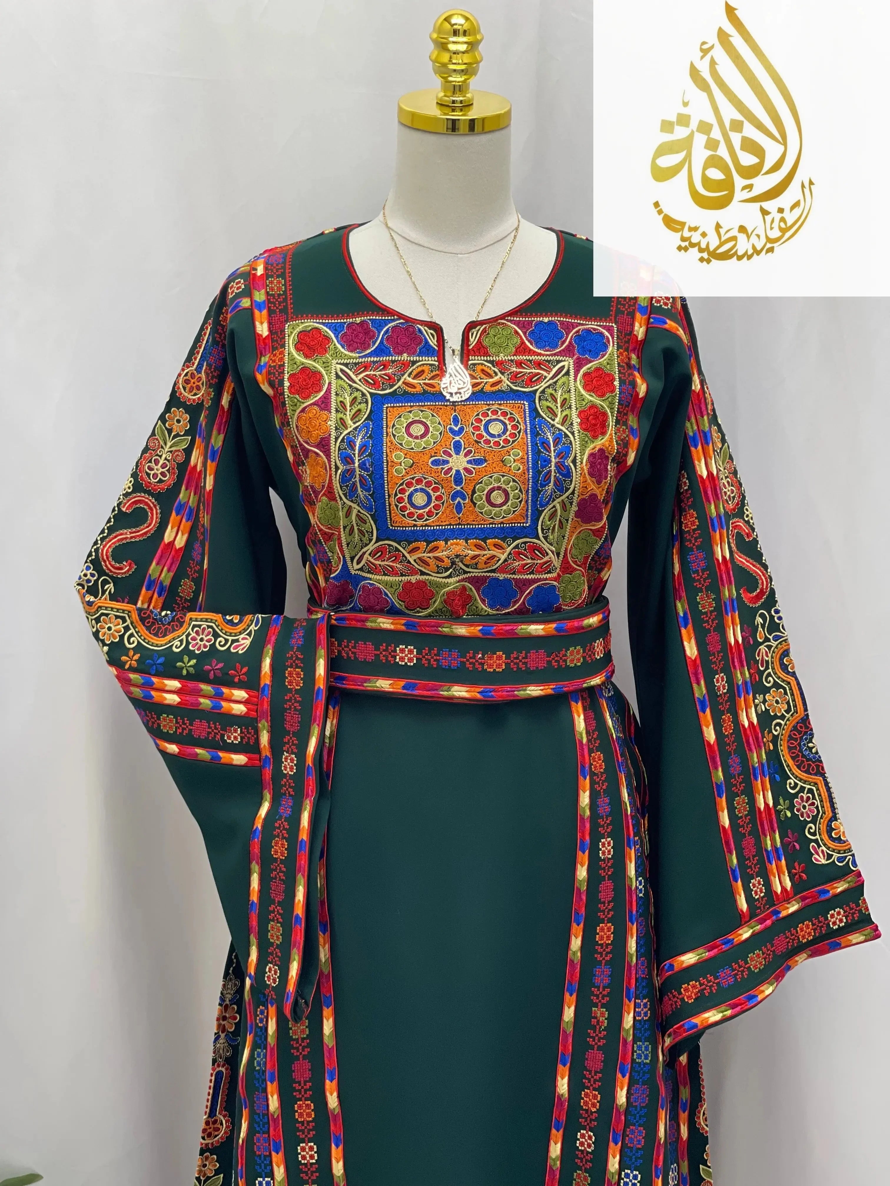 Embroidered Palestinian dress by Palestinian Elegance with colorful traditional embroidery on green fabric