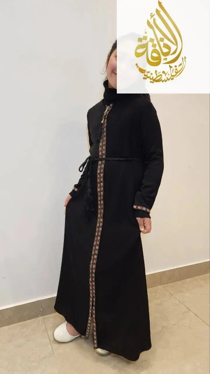 Girl wearing black embroidered abaya for girls with patterned trim and tassel detail