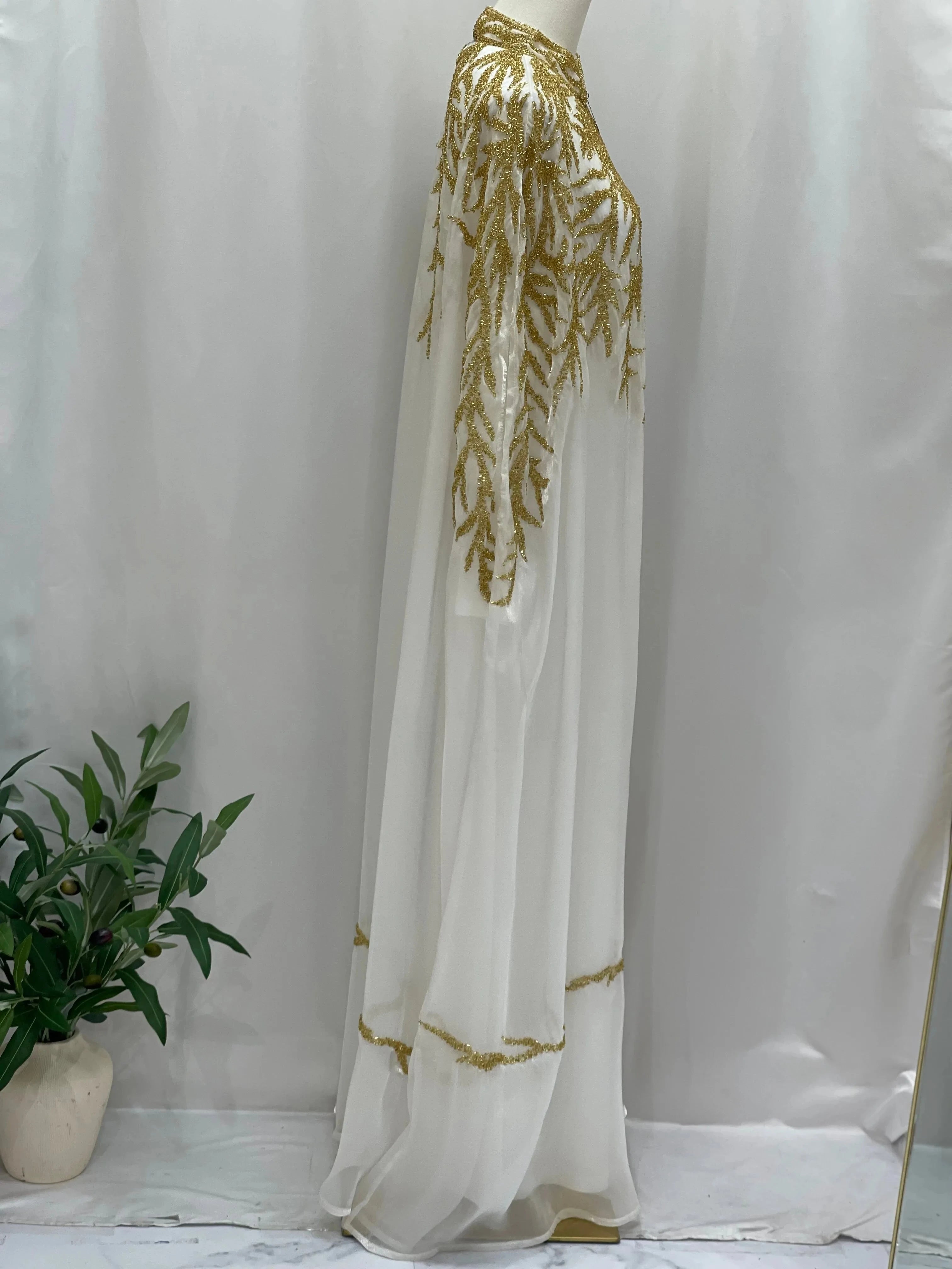White traditional embroidery cape with intricate gold detailing by Palestinian Elegance displayed on mannequin