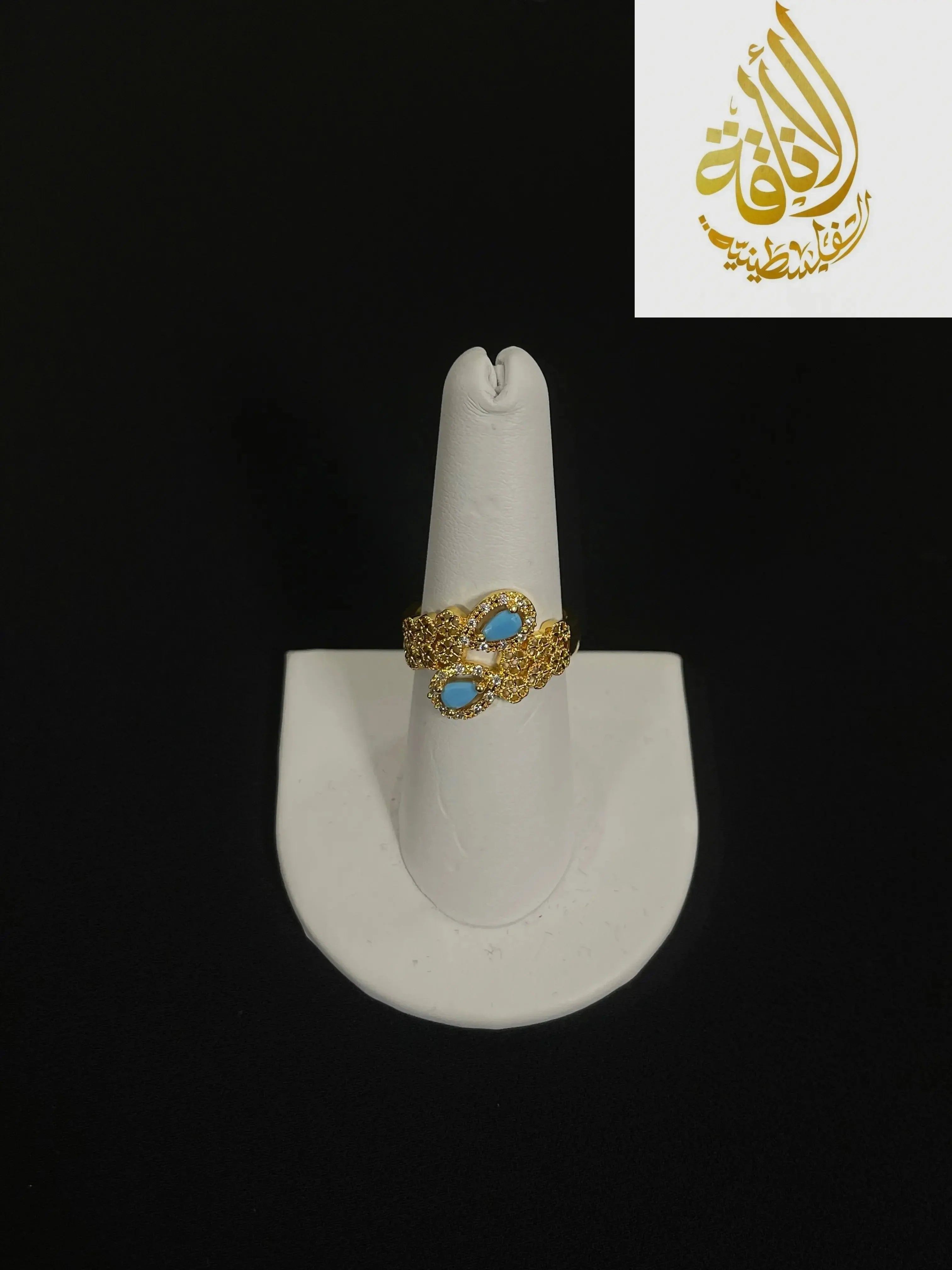 Palestinian gold jewelry set featuring a gold ring with blue stones on a white display stand