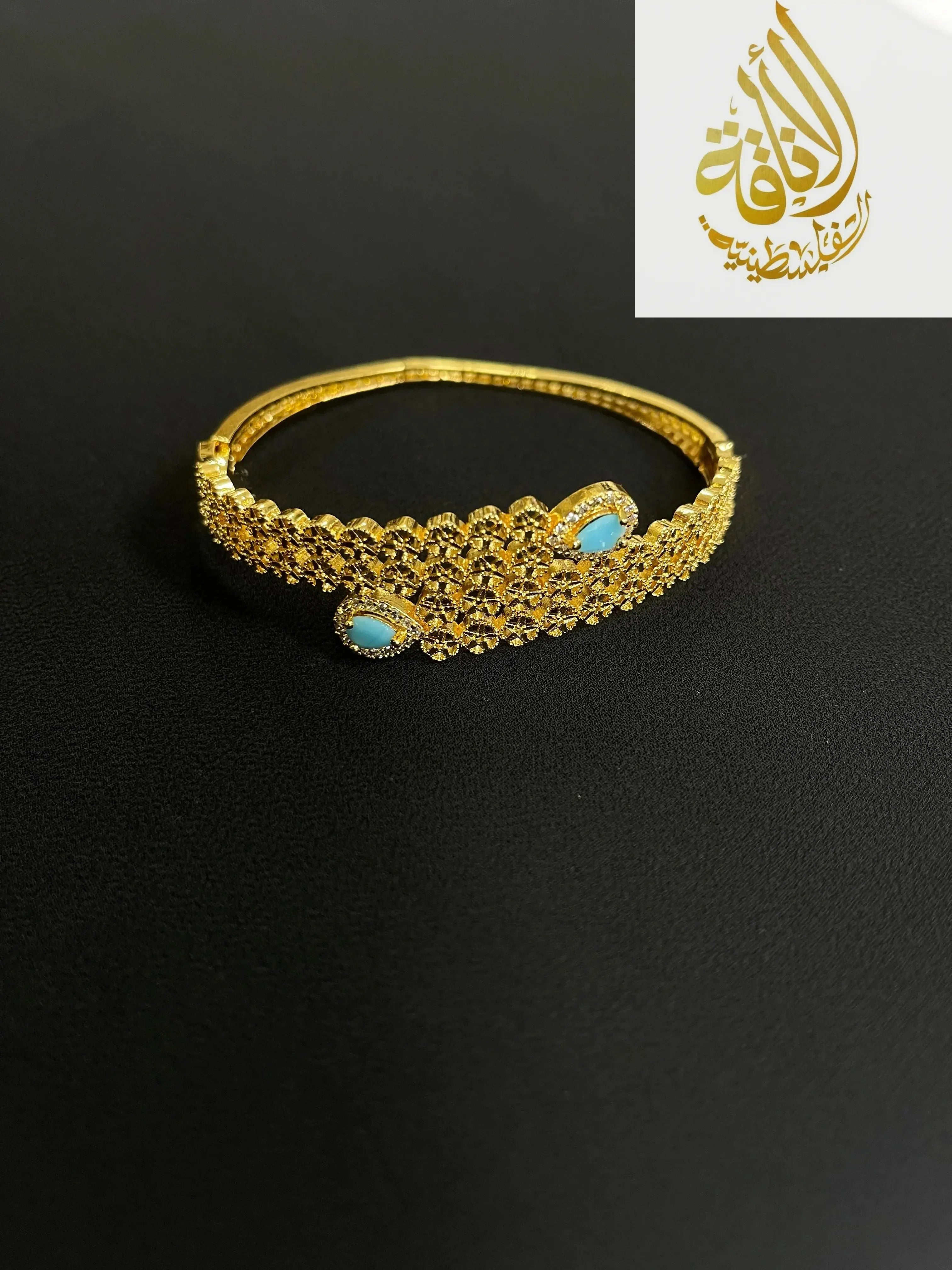 Palestinian gold jewelry set featuring an intricate gold bracelet with turquoise accents on black background