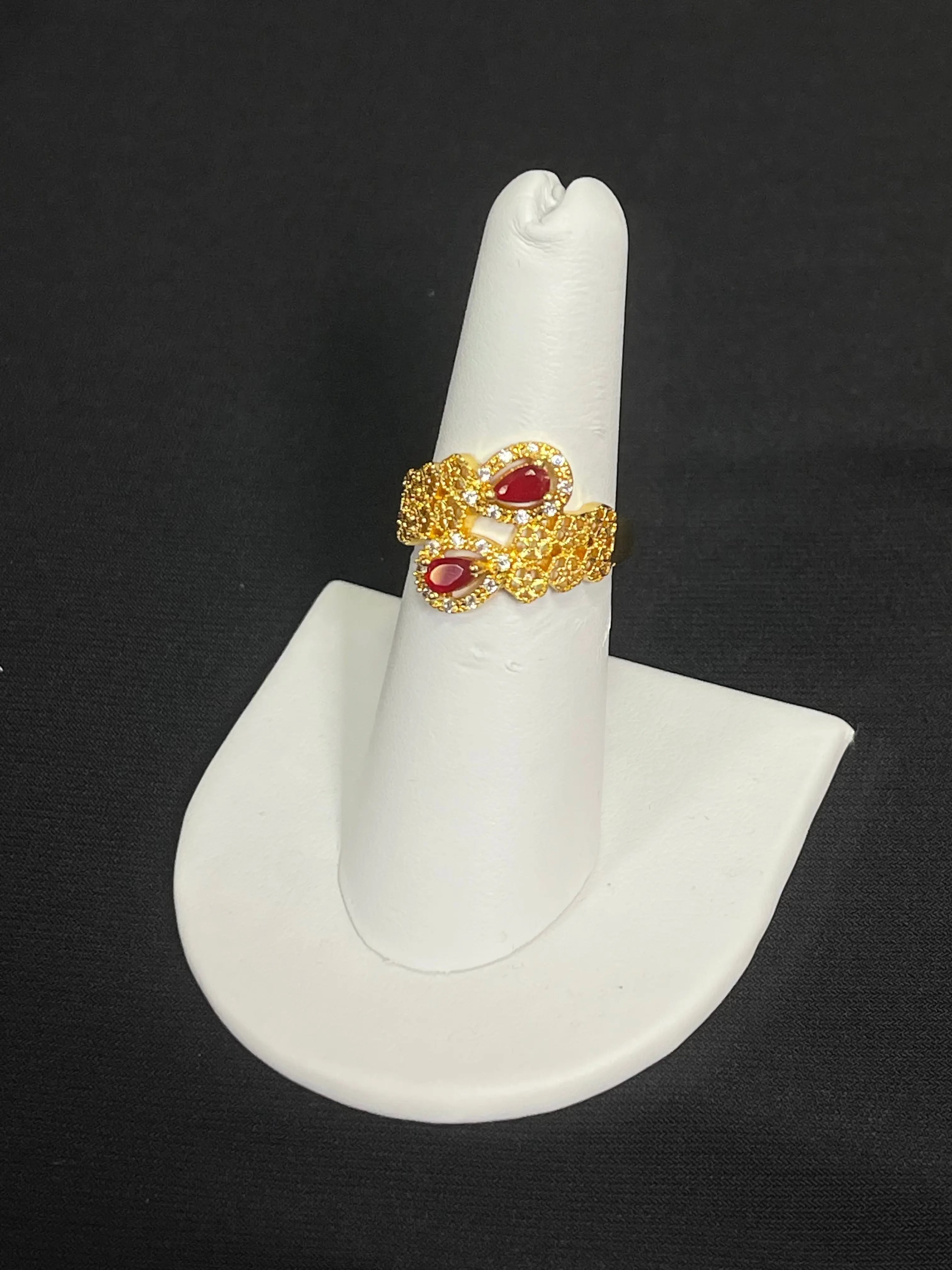 Palestinian gold jewelry set featuring an intricate gold ring with red gemstone accents displayed on a white ring holder