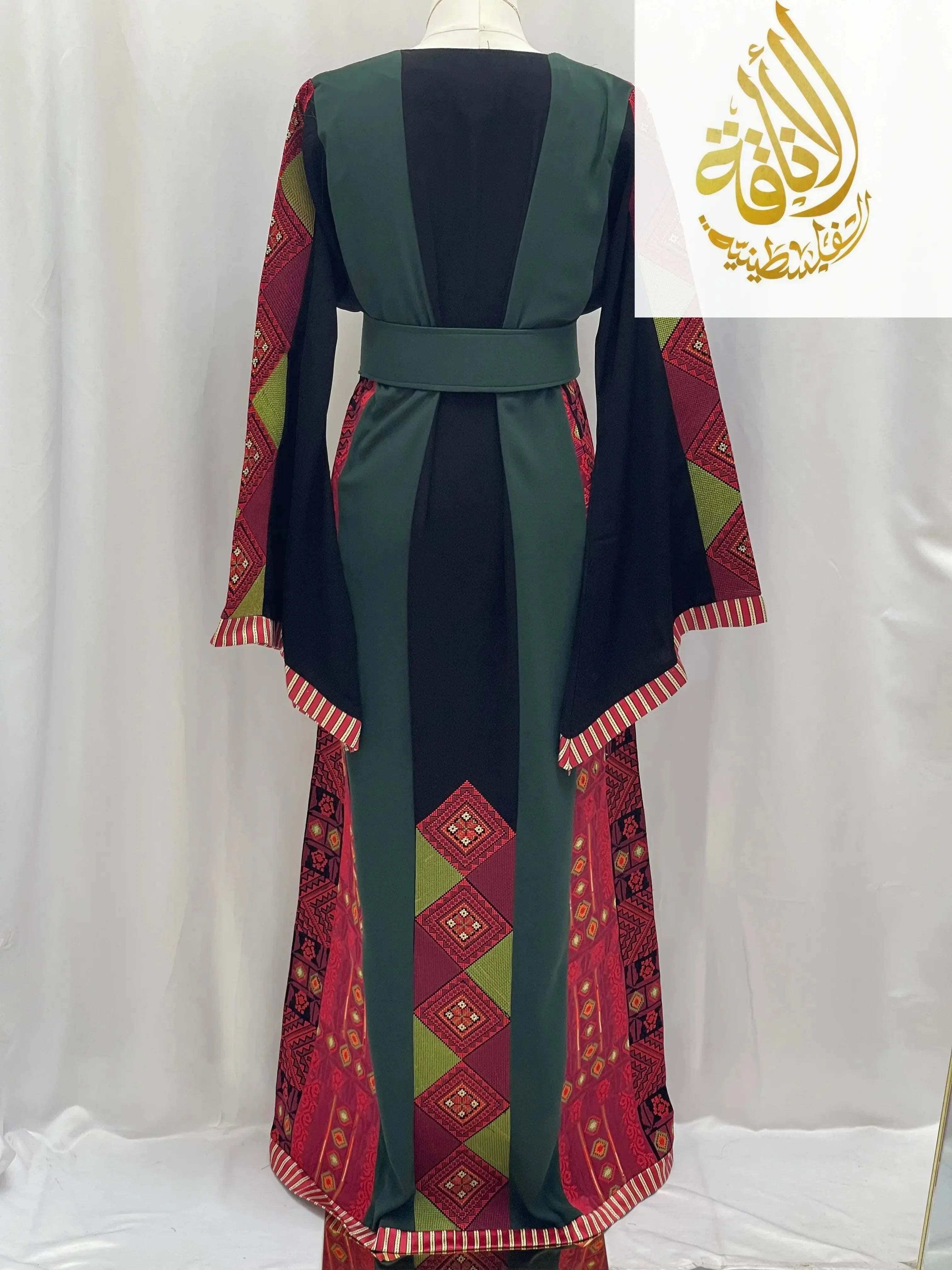 Embroidered Palestinian thoub by Palestinian Elegance featuring traditional red and green geometric patterns on black fabric