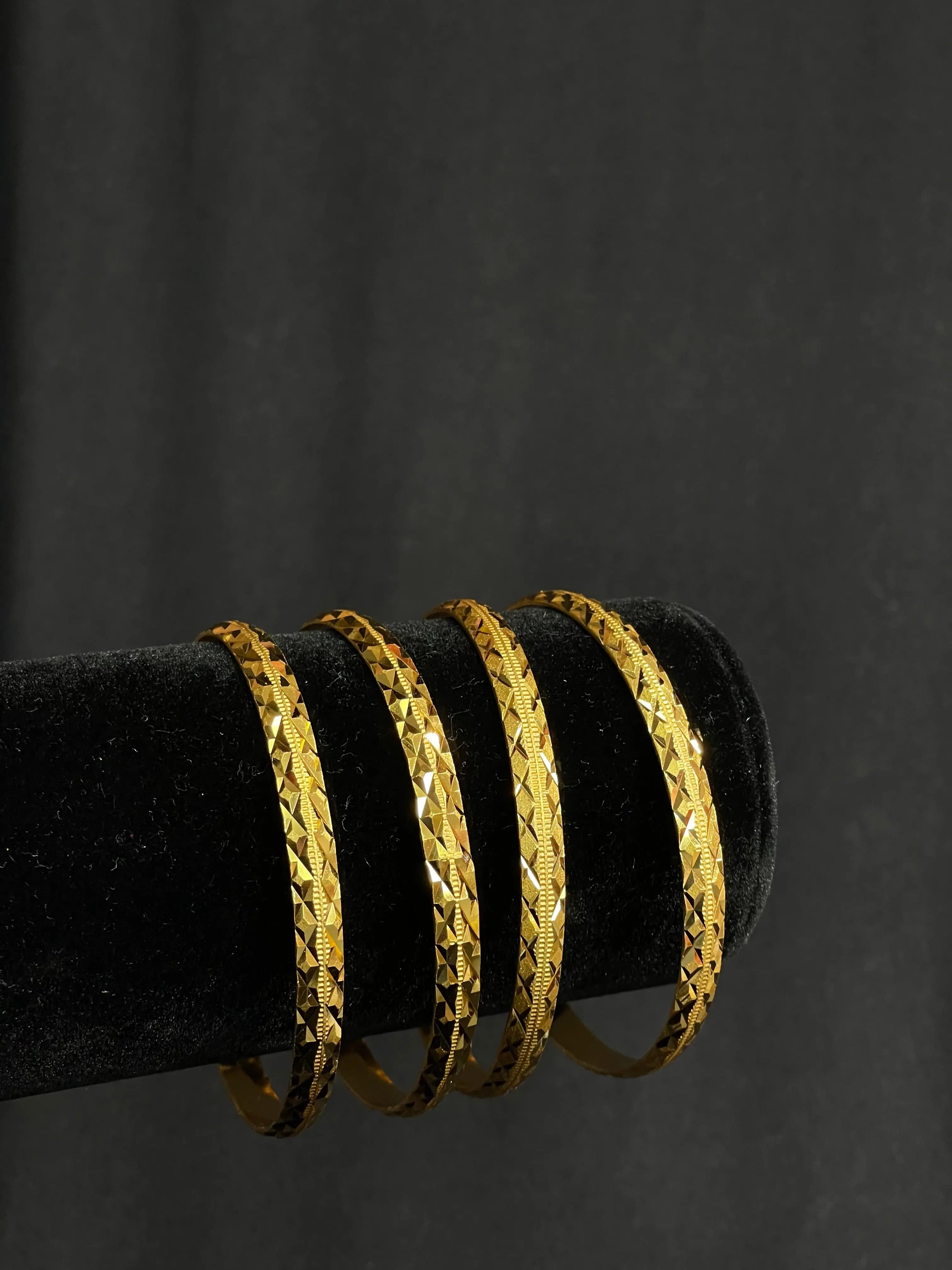 Zuhra gold bangles bracelet set in imitated gold by Palestinian Elegance displayed on black stand