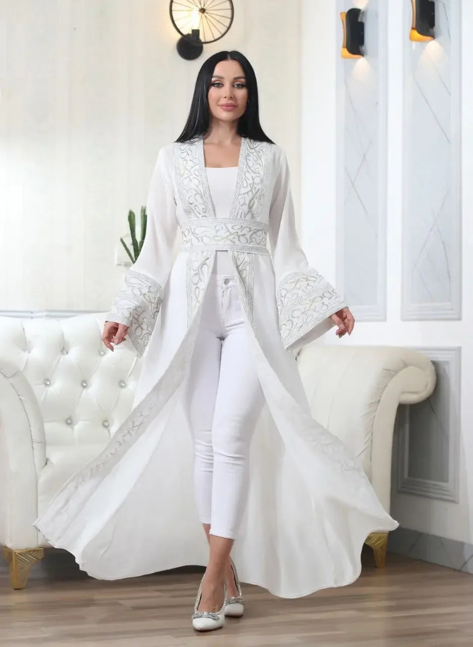 White Arabic letter embroidered cardigan worn by woman over white outfit in stylish living room