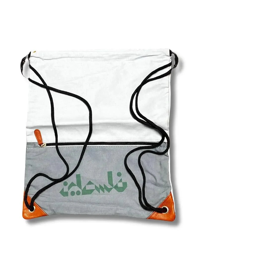 Handmade Palestine backpack with white and gray fabric, black drawstrings, and brown corner accents